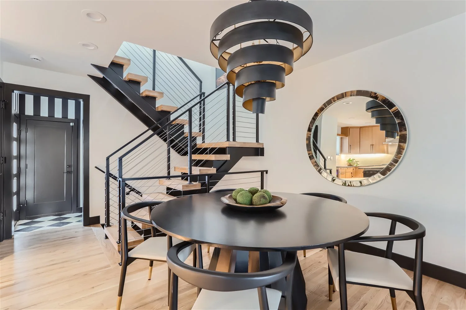 Dramatic dining room with spiral light fixture centered over table with wishbone chairs
