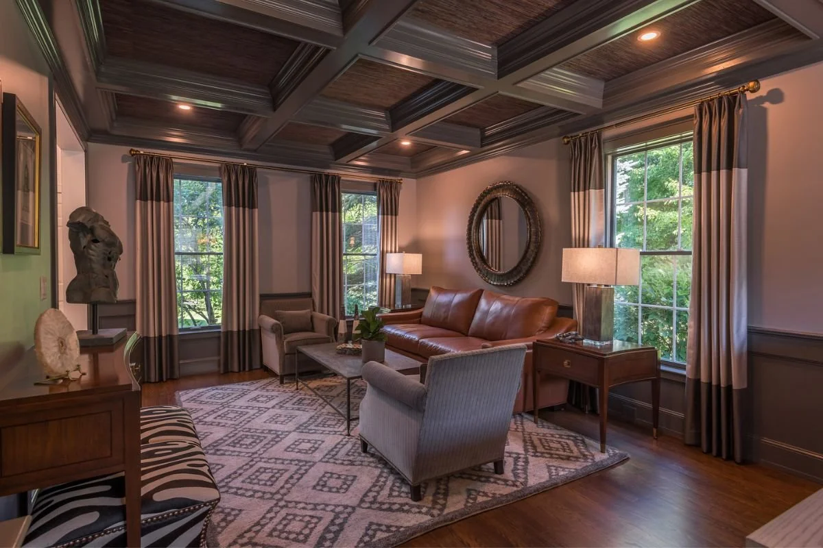 Intimate, low lit sitting room with coffered ceiling, 2 club chairs and leather sofa