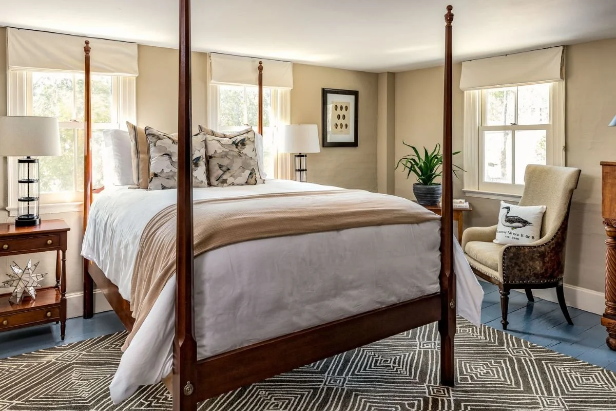 Airy bedroom with Shaker four poster bed and calm neutral colors, painted blue floors for accent