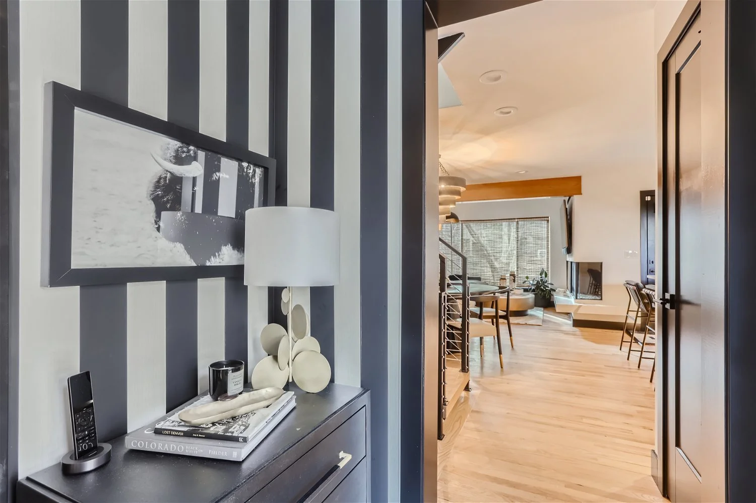 Bold foyer with vertical black and white striped wallpaper and styled entryway table