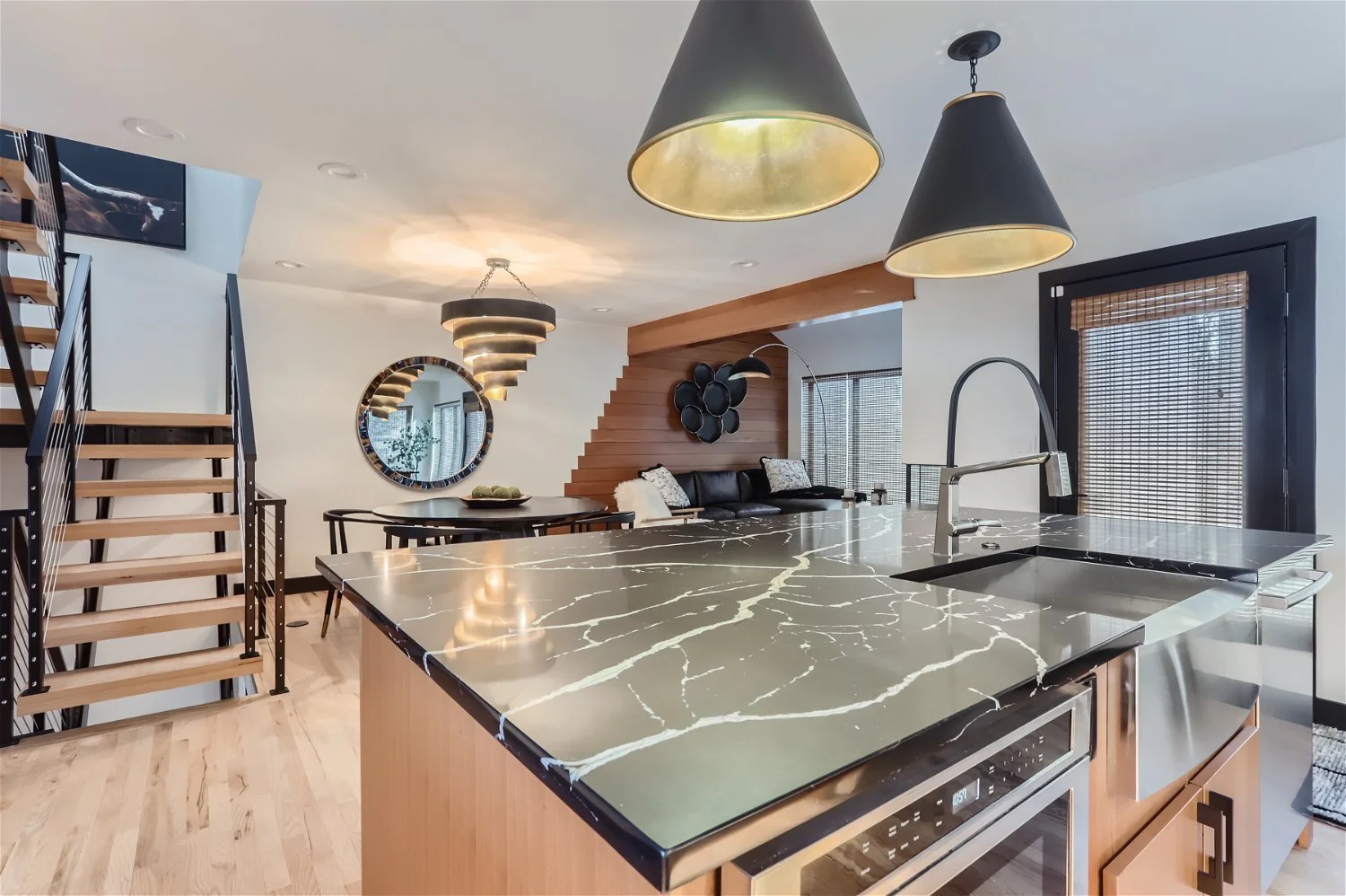 Open concept kitchen with Black Panda Marble countertops and black and gold pendant lighting