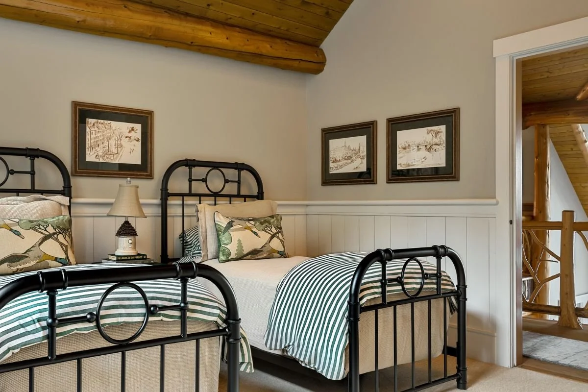 Matching antique iron twin beds in guest room with shiplap wainscoting