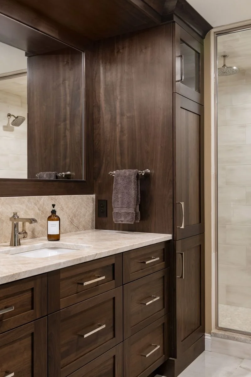 Custom cabinetry in mahogany and variegated quartz tie the bath in the global theme