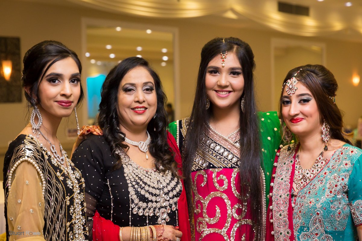 Four women in colorful traditional attire at a formal event, smiling for the camera.