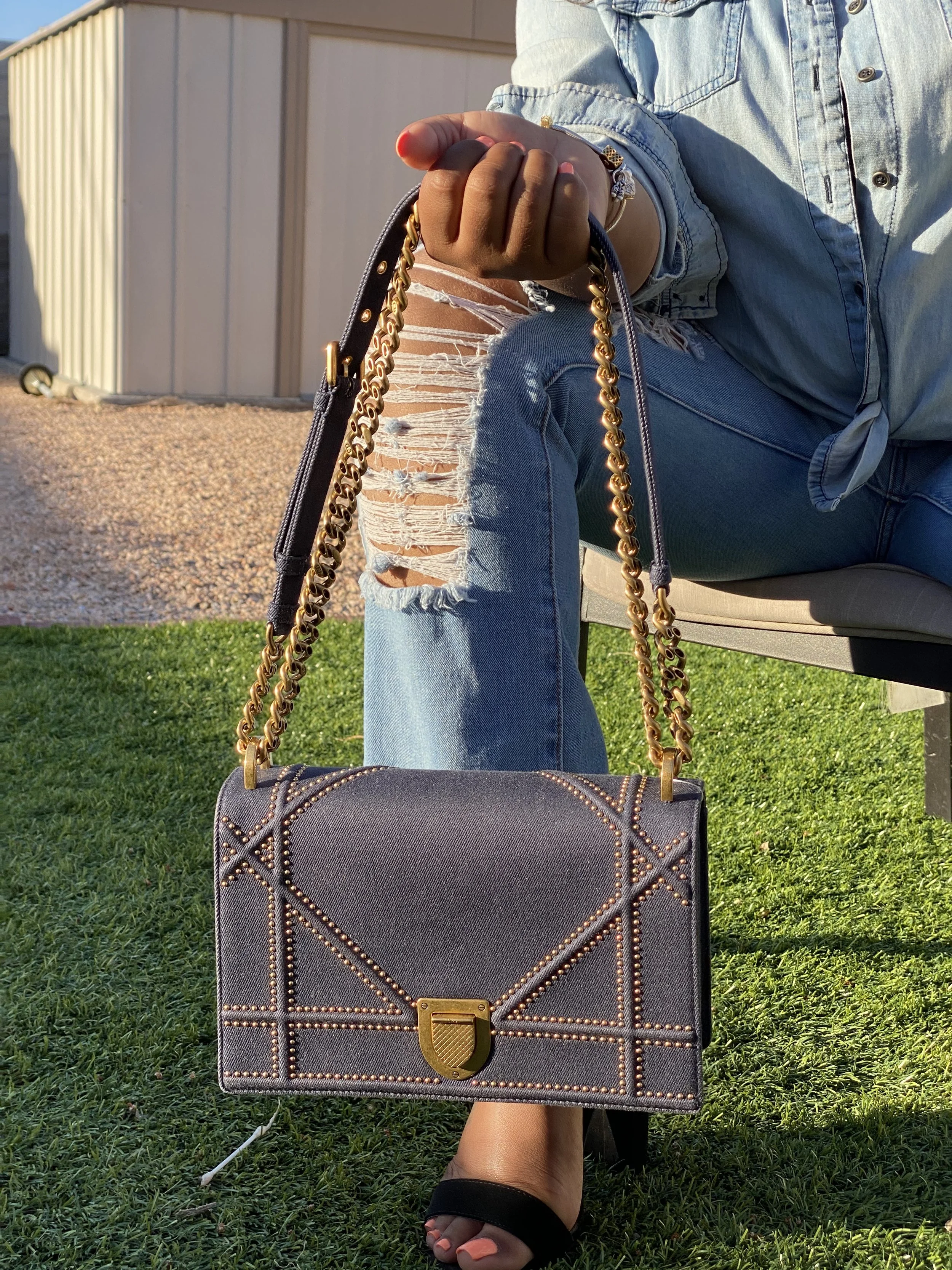 Woman holding a denim chain strapped Celine crossbody bag.