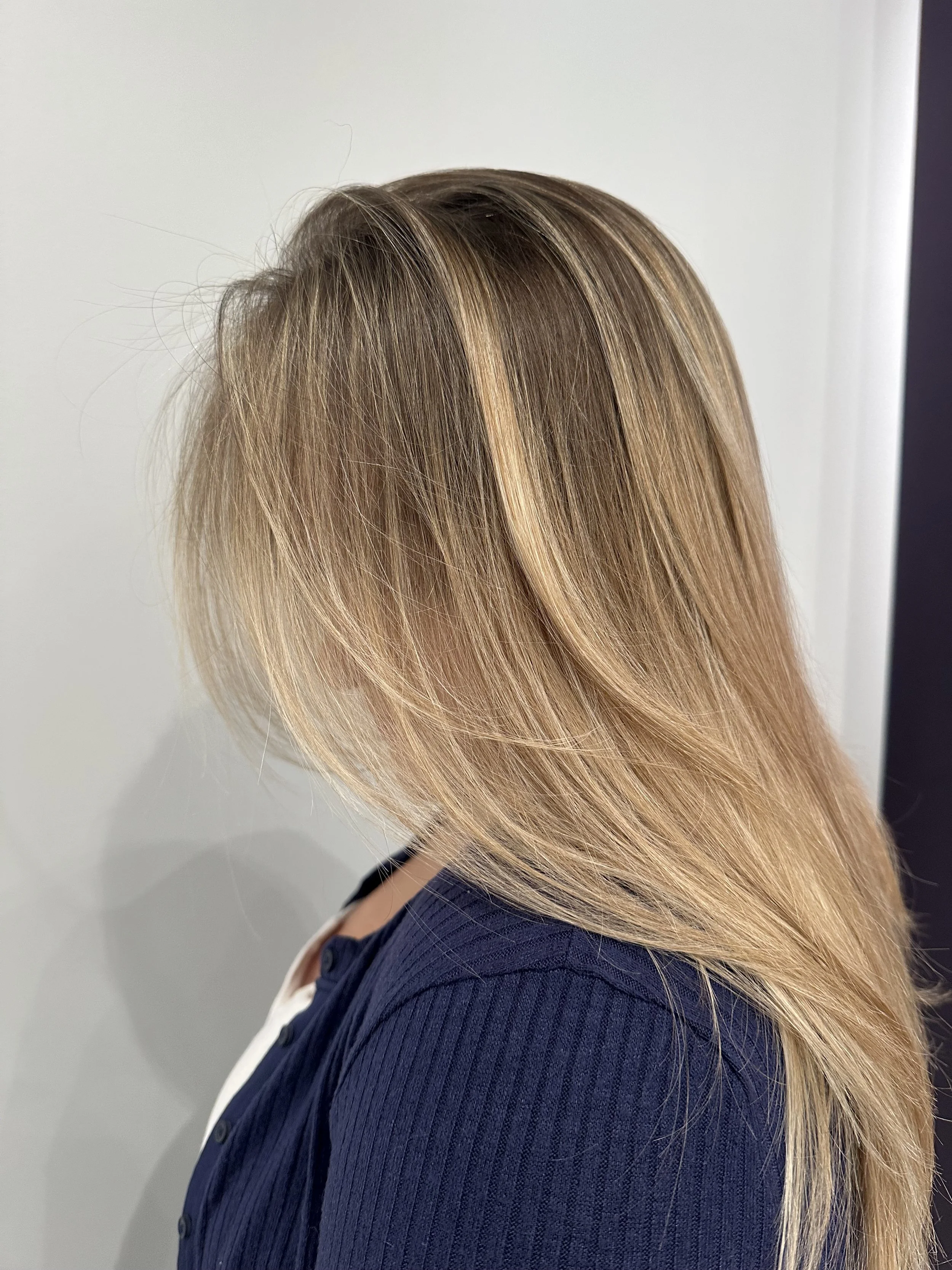 Side view of a person with long, straight, blonde hair wearing a navy blue jacket.
