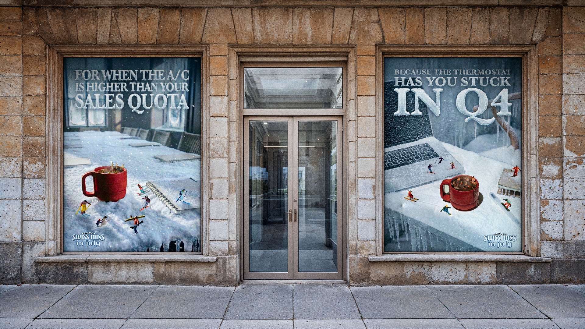 Two advertisement posters on a brick building featuring snowy scenes with miniature model skiers, a large red mug with hot chocolate or coffee, and text about Swiss Miss hot chocolate. The posters promote Swiss Miss in July with humorous ski-related holiday sales notices.