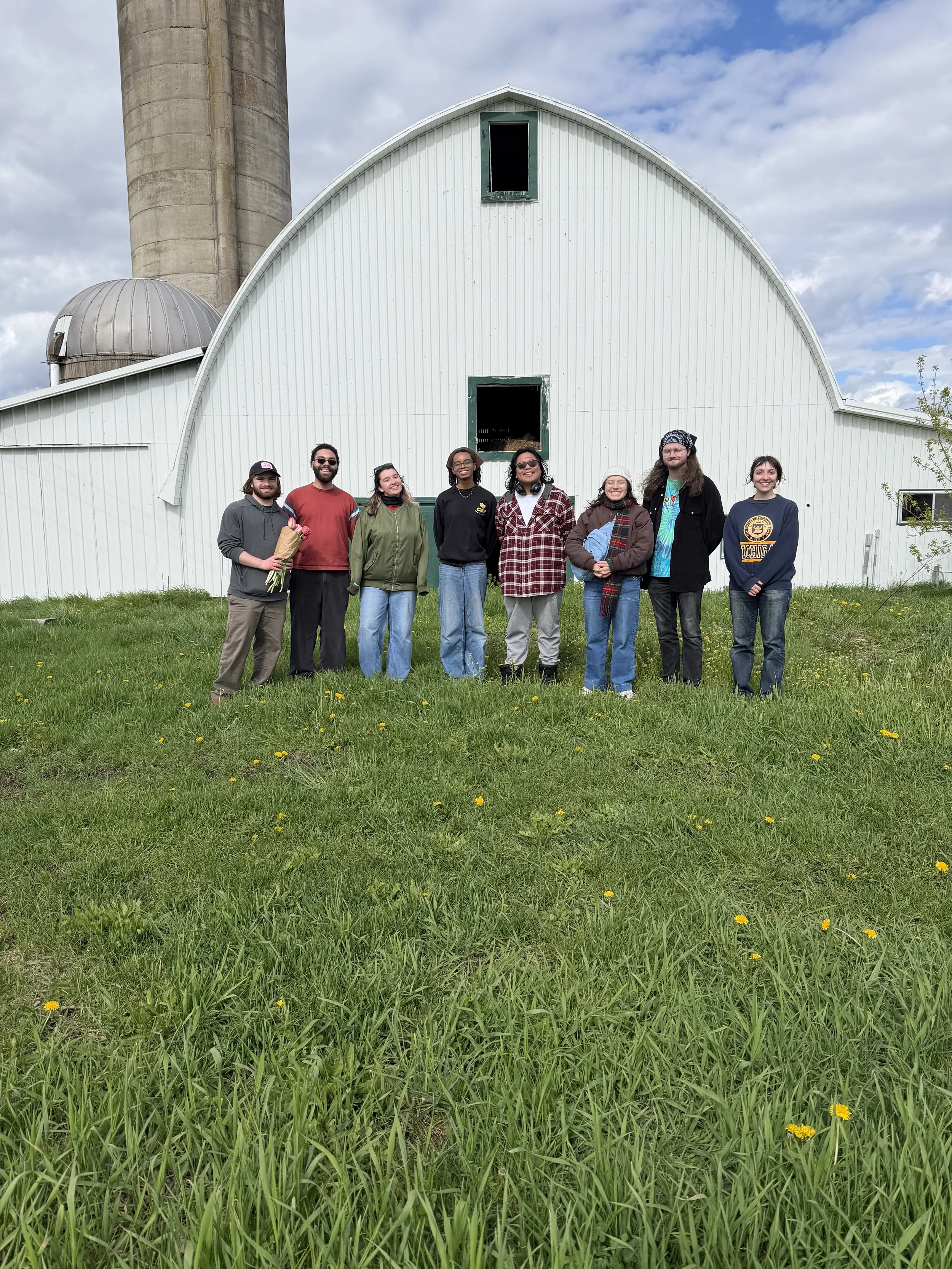 Several students in front of a white barn