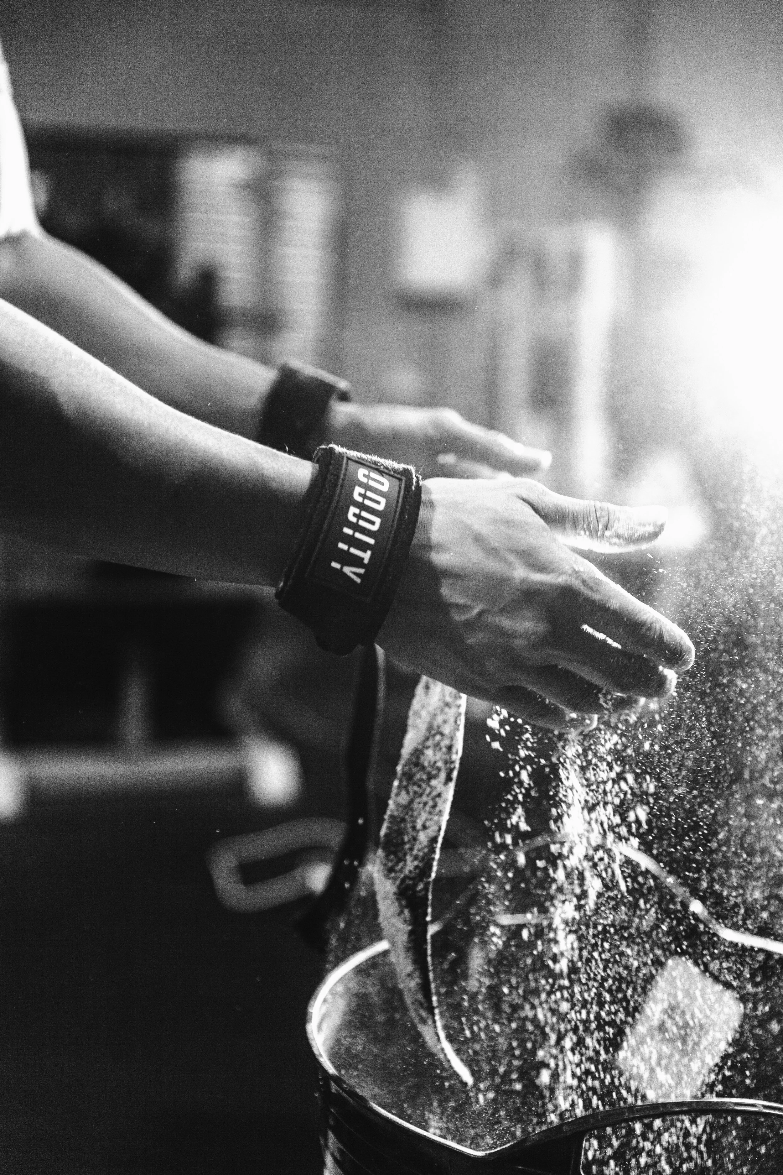 Close-up of a person pouring chalk into a bucket, with chalk dust dispersing in the air, in a fitness or gym setting.