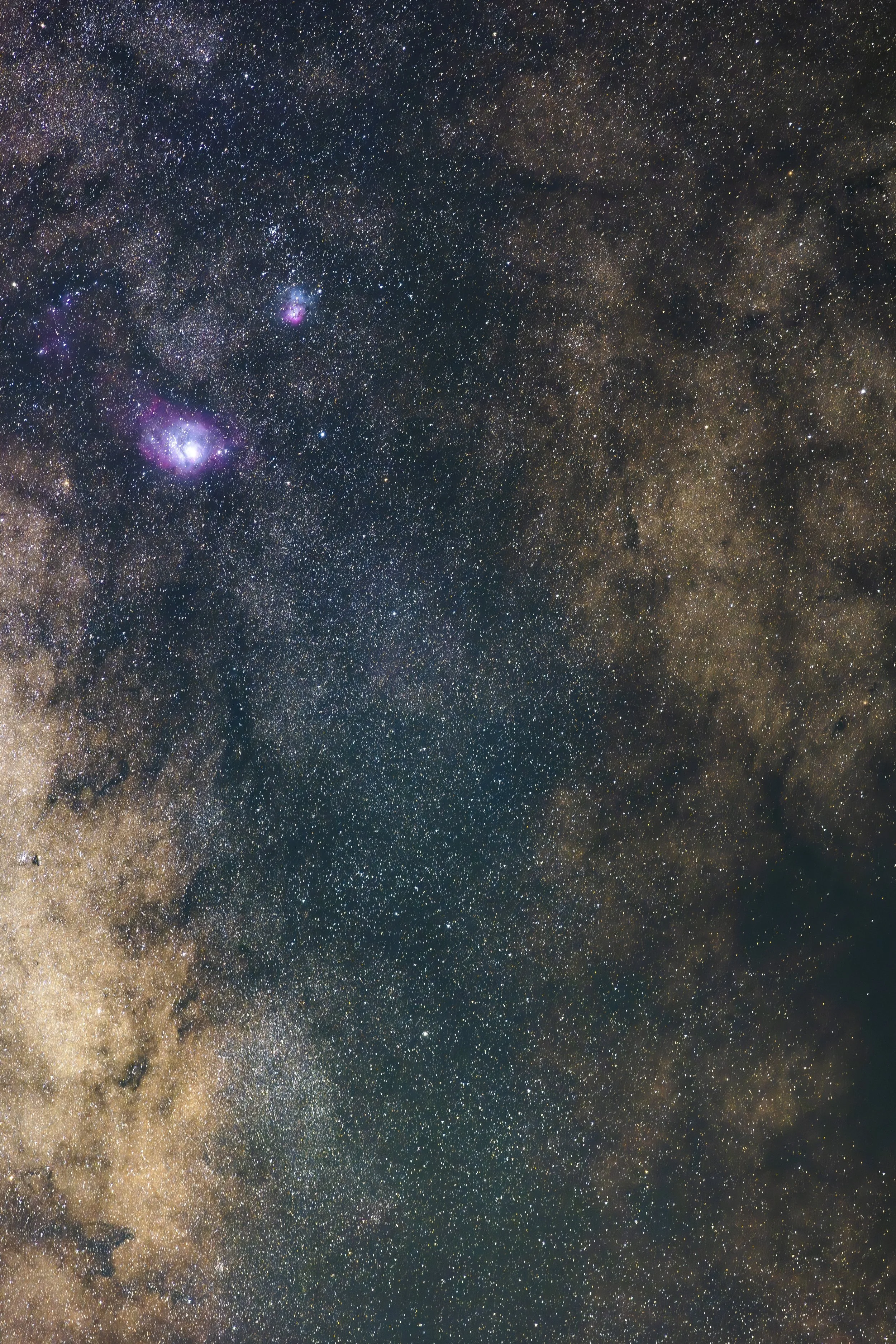 Starry night sky with dense clusters of stars and colorful nebulae in the Milky Way galaxy.