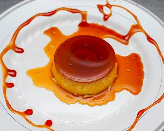 Caramel flan dessert with caramel sauce drizzled on a white plate.