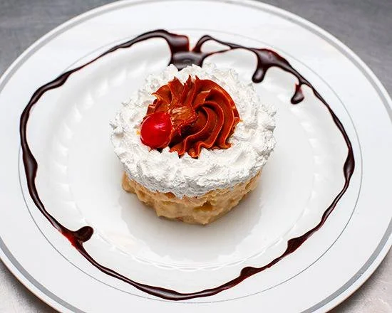 Celebration cake with whipped cream, chocolate frosting, a cherry, and chocolate syrup on a white plate.