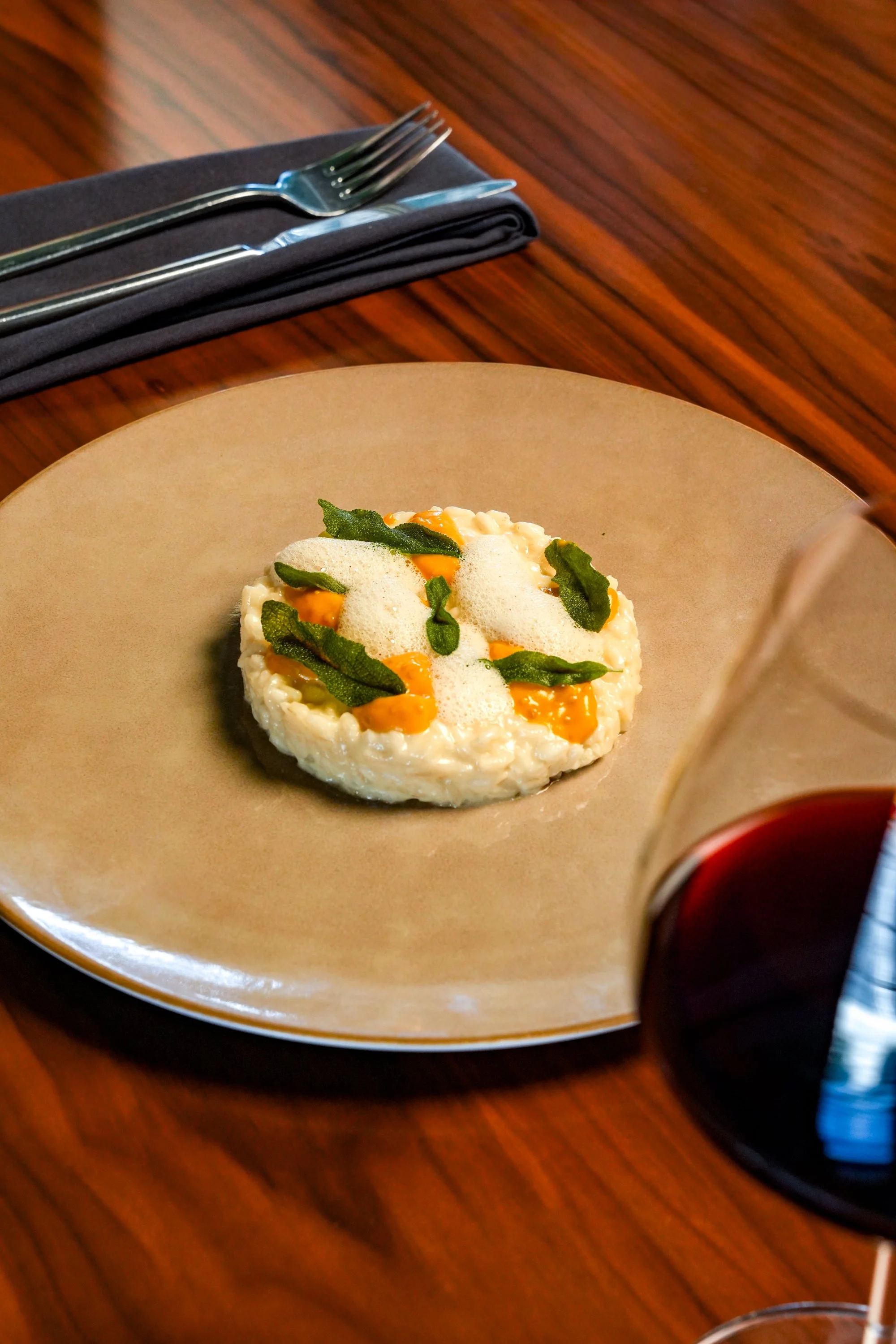 a small serving of risotto paired with green leaves and a yellow dollop