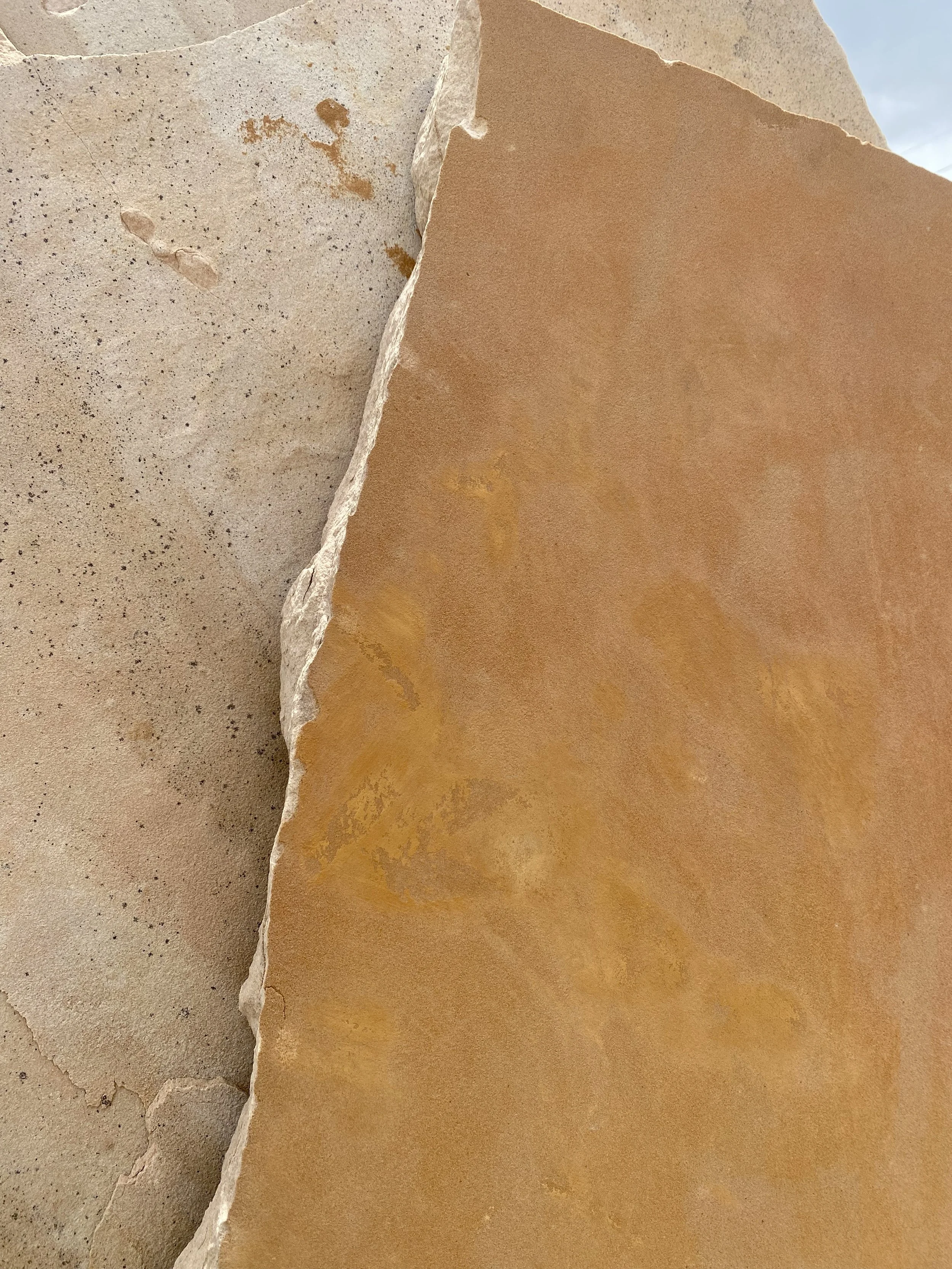 Close-up of layered beige, tan, and light brown stones with rough and smooth textures.