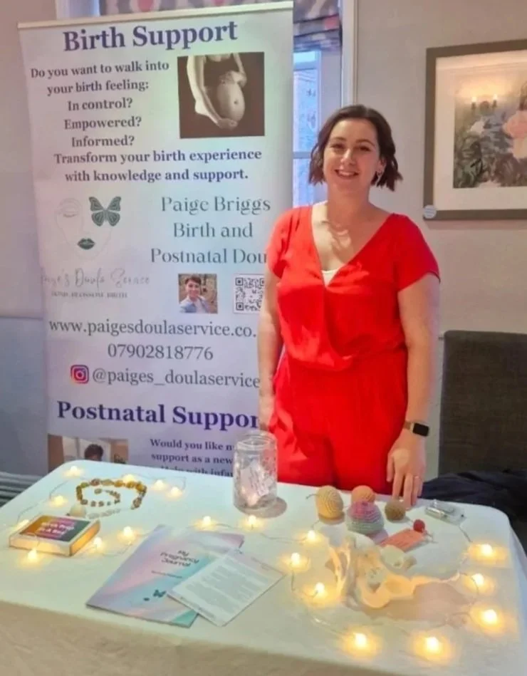 Paige beside her doula support information stand.