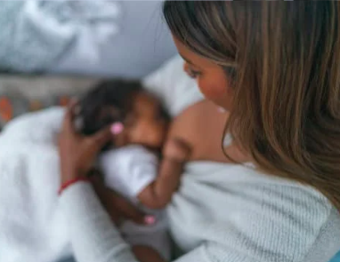 Mother breastfeeding her baby while seated.