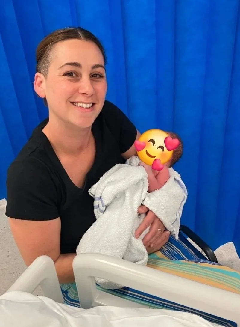 Doula holding a newborn baby in a hospital room.