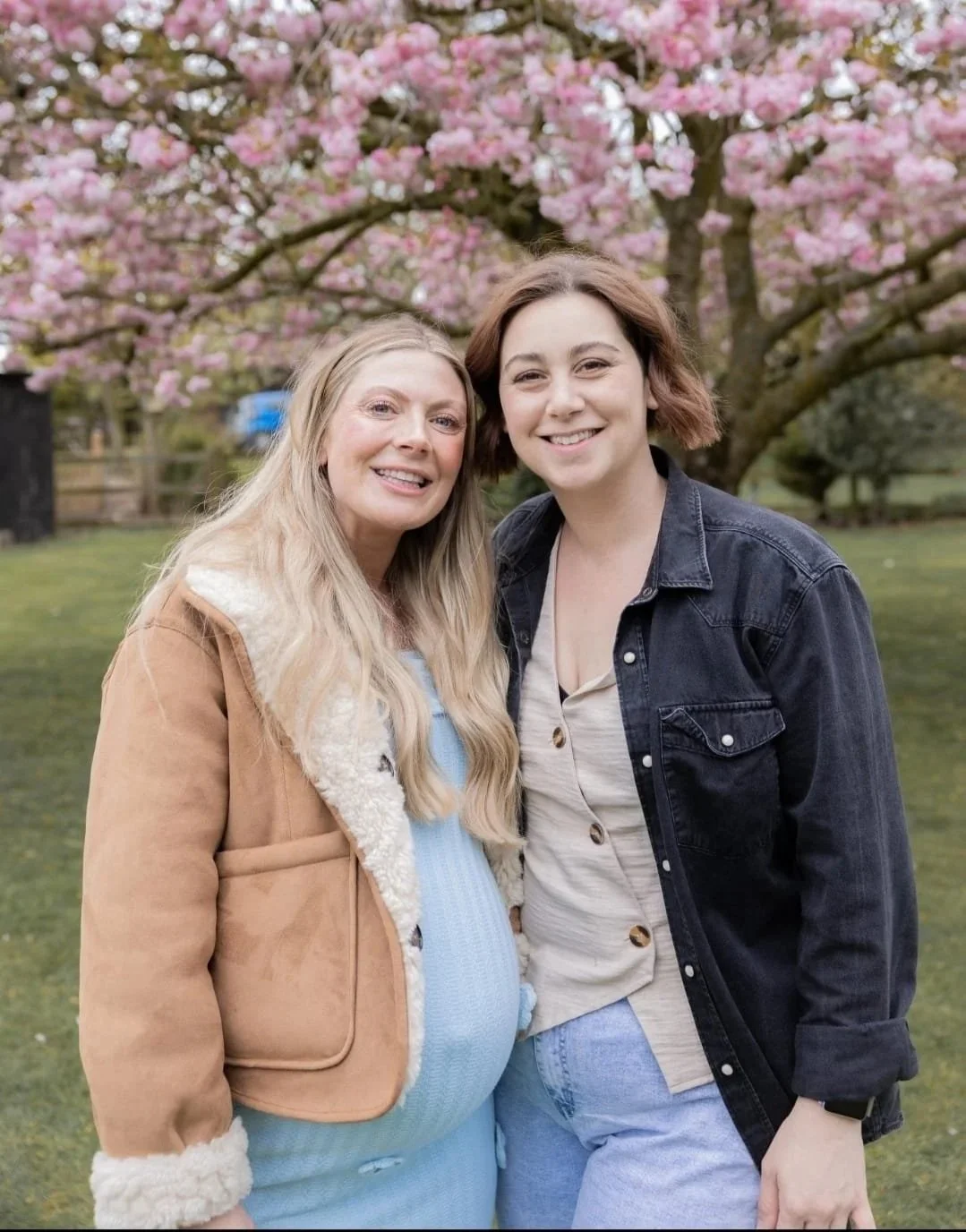 Paige standing with a friend beneath a flowering tree.