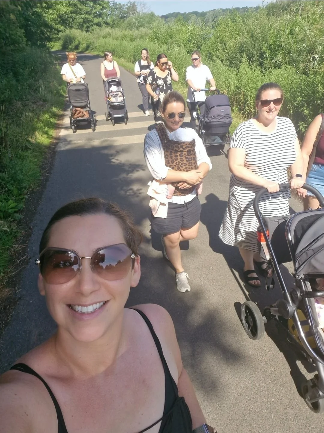 Paige walking outdoors with parents and their babies.