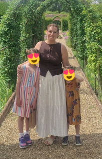 Paige standing outdoors with her two daughters.