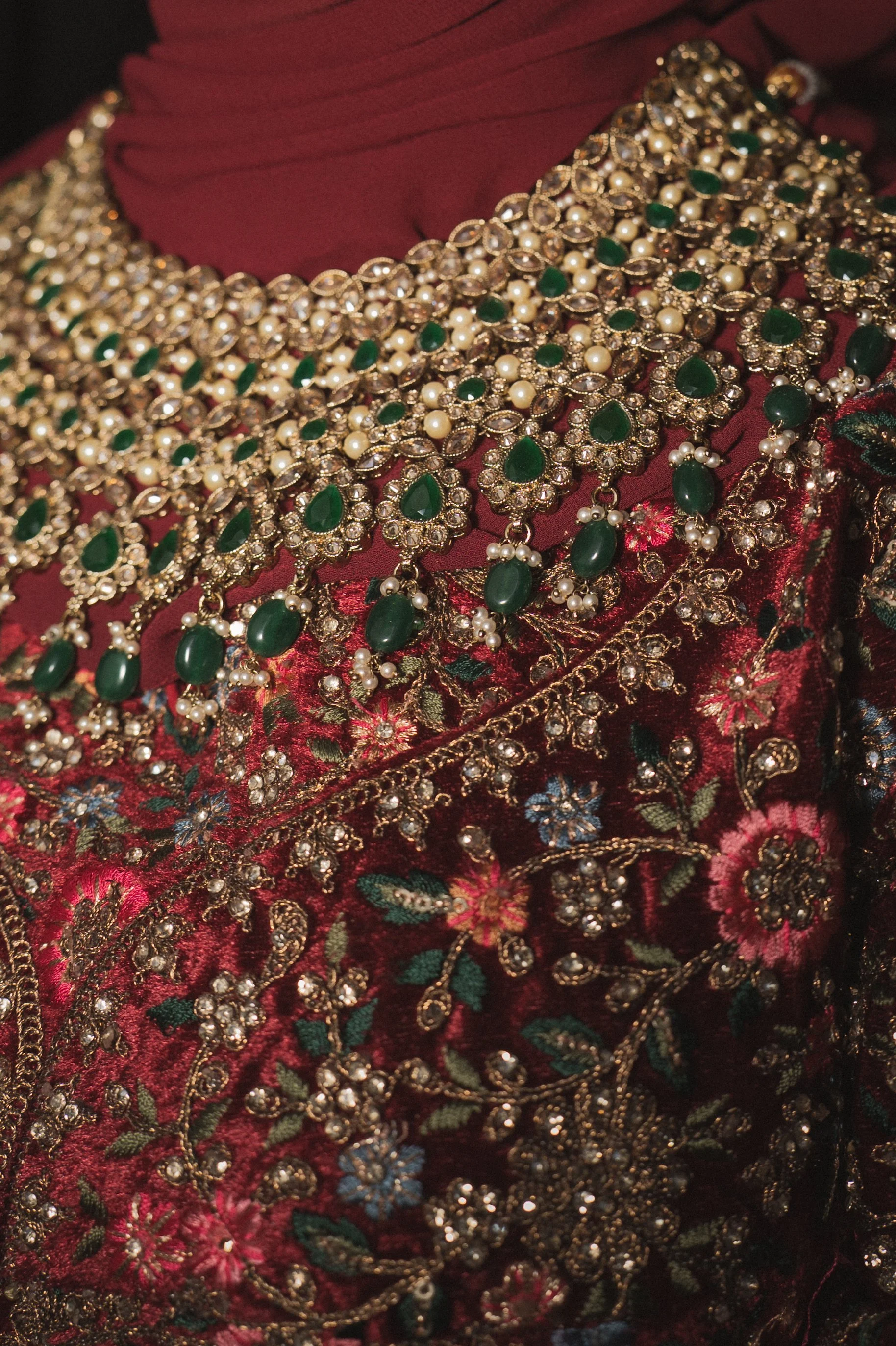 Close-up of ornate jewelry and embroidered fabric with floral pattern.