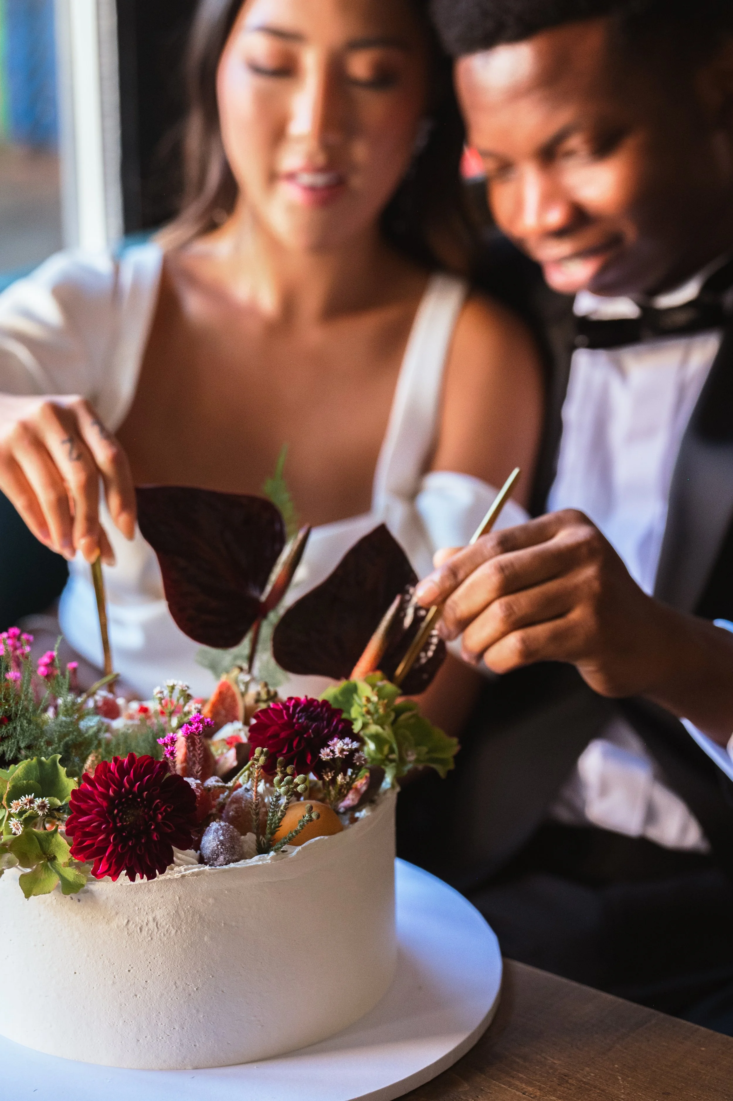 Couple cutting floral-decorated cake in formal attire
