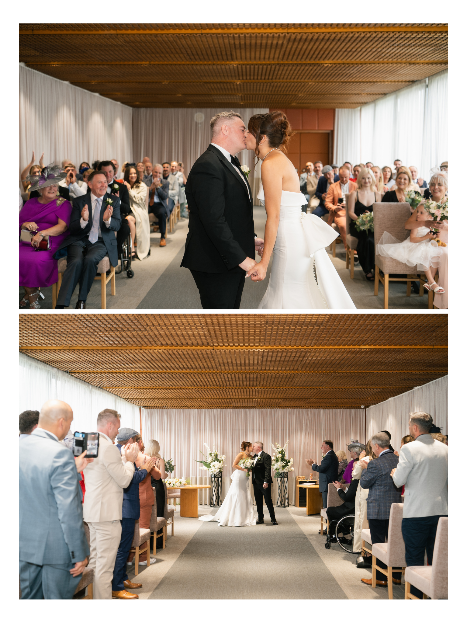 A bride and groom kiss during their wedding ceremony held indoors. Guests are seated on both sides, clapping and watching the couple.