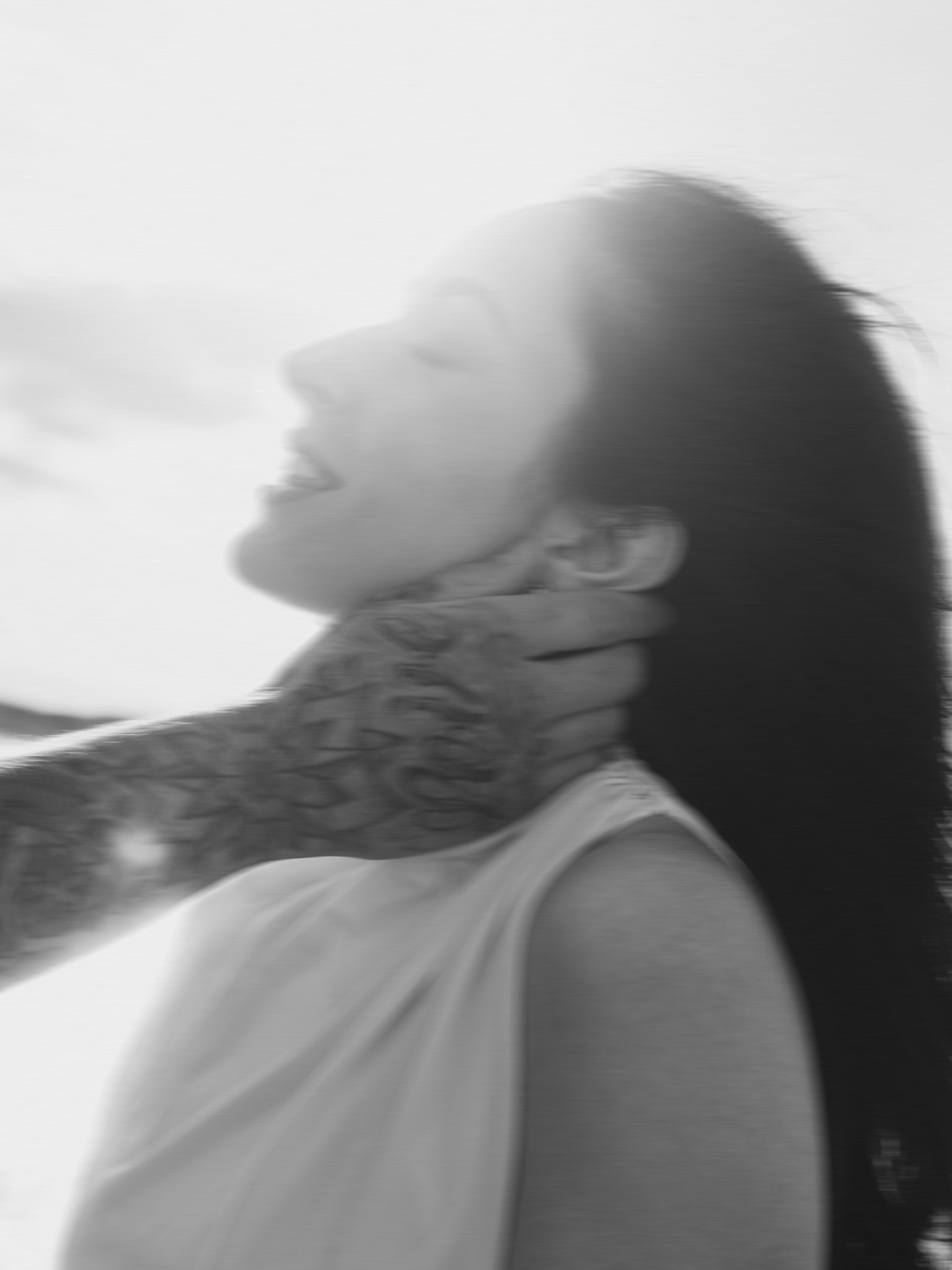 Blurred black-and-white side profile of a woman with long hair, appears to be in motion.