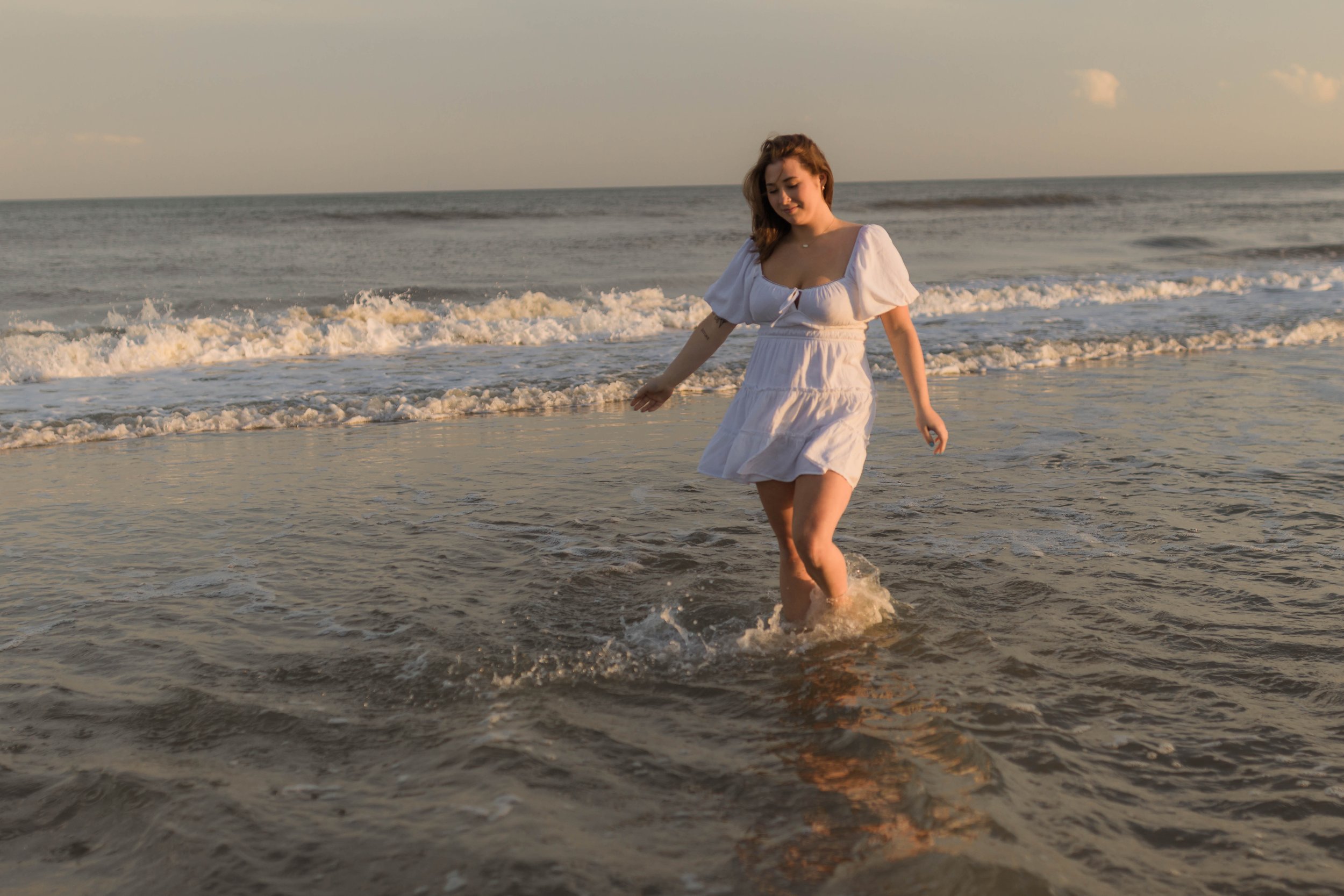Mother and three daughters smiling and walking barefoot along the shoreline at sunset, Huntington Beach State Park
