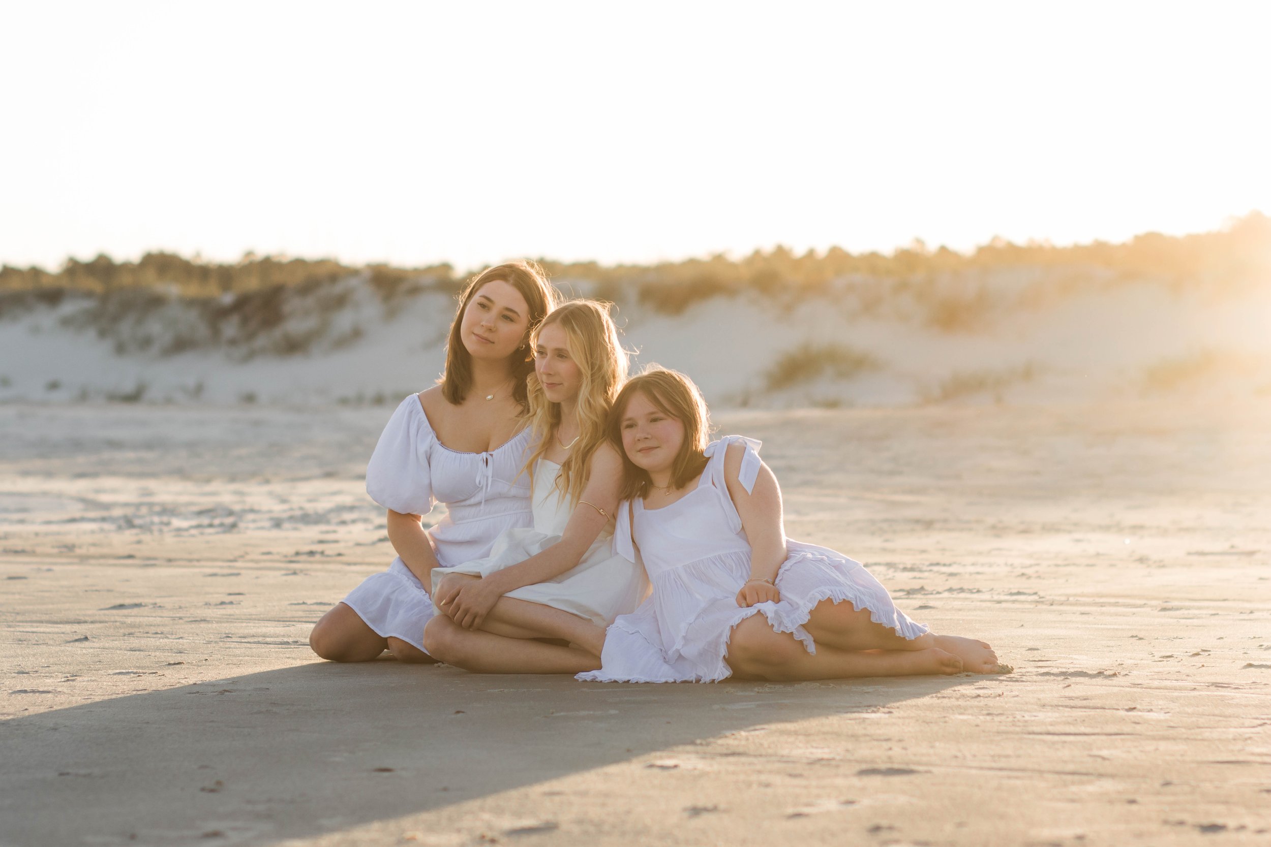 Mother and three daughters smiling and walking barefoot along the shoreline at sunset, Huntington Beach State Park