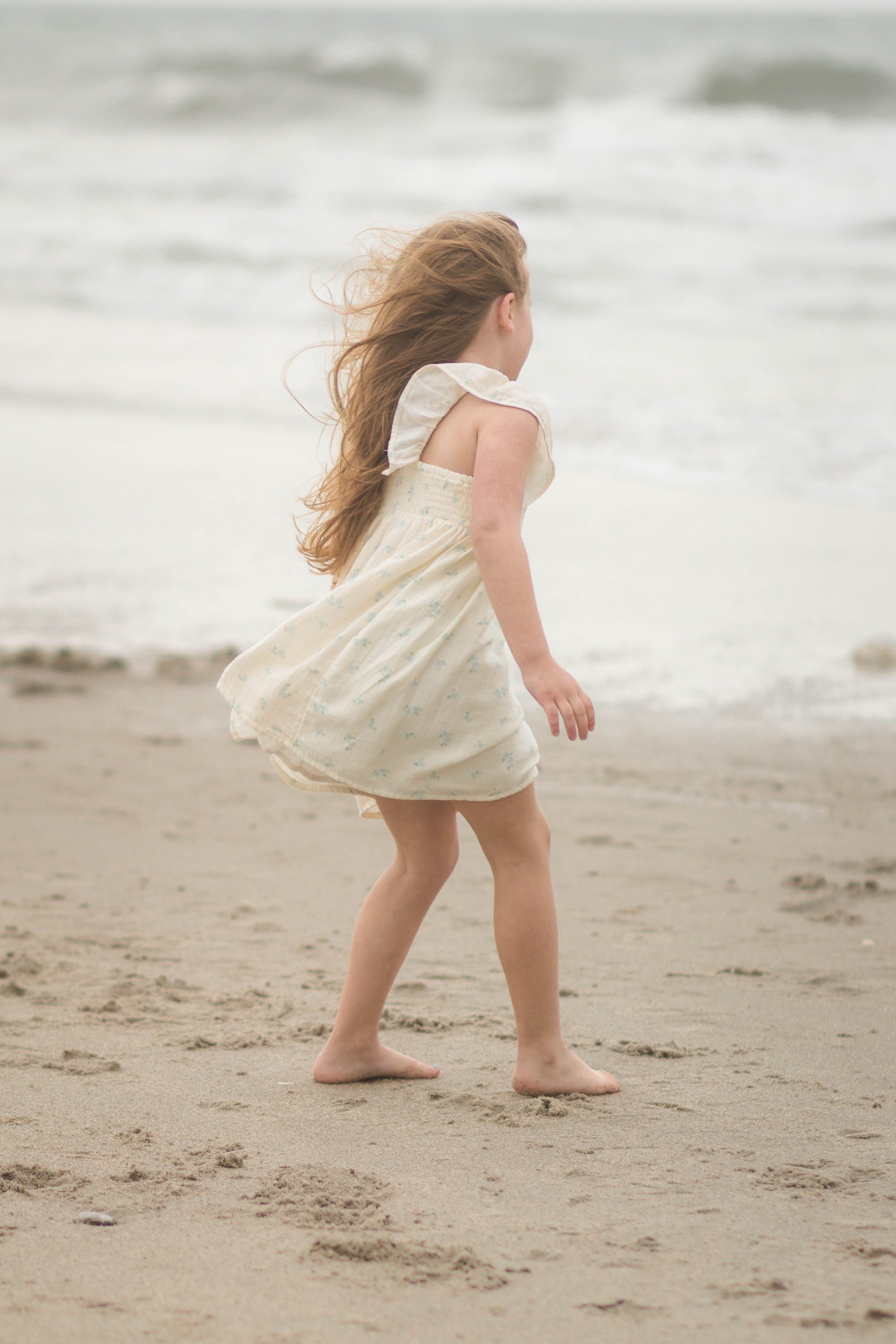 Family playing together during a windy beach photo session at Springmaid Pier in Myrtle Beach.