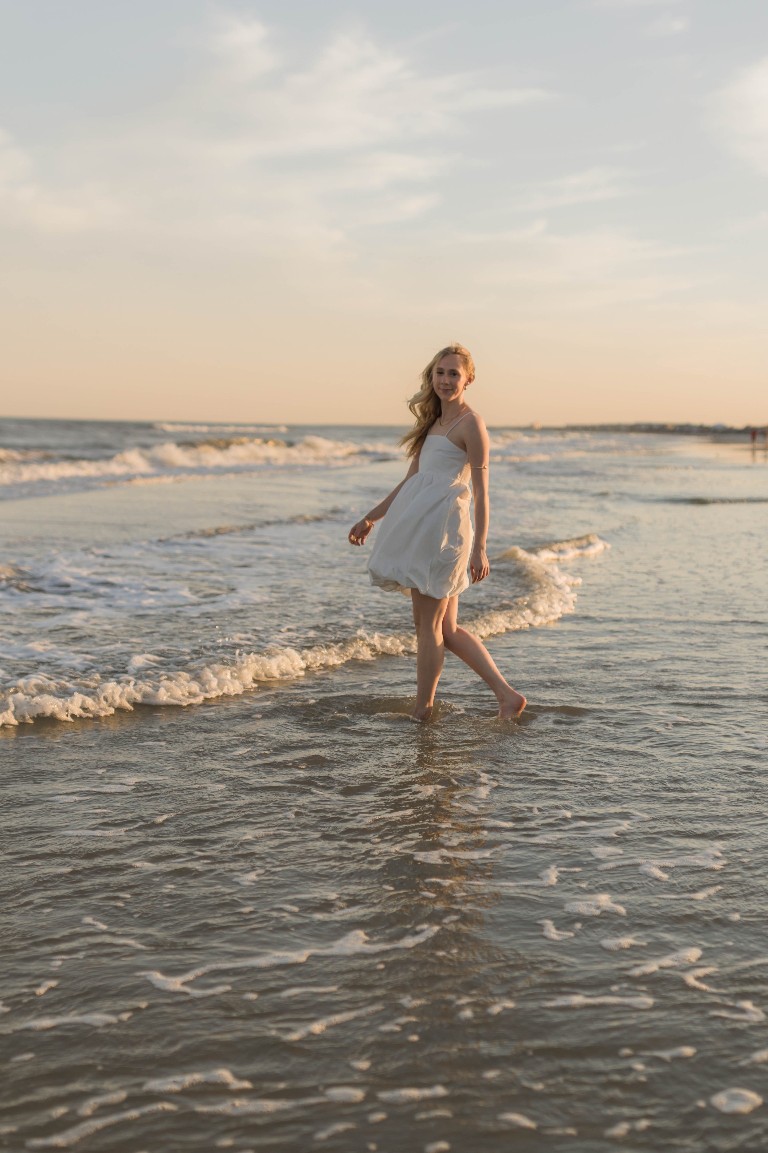 Mother and three daughters smiling and walking barefoot along the shoreline at sunset, Huntington Beach State Park