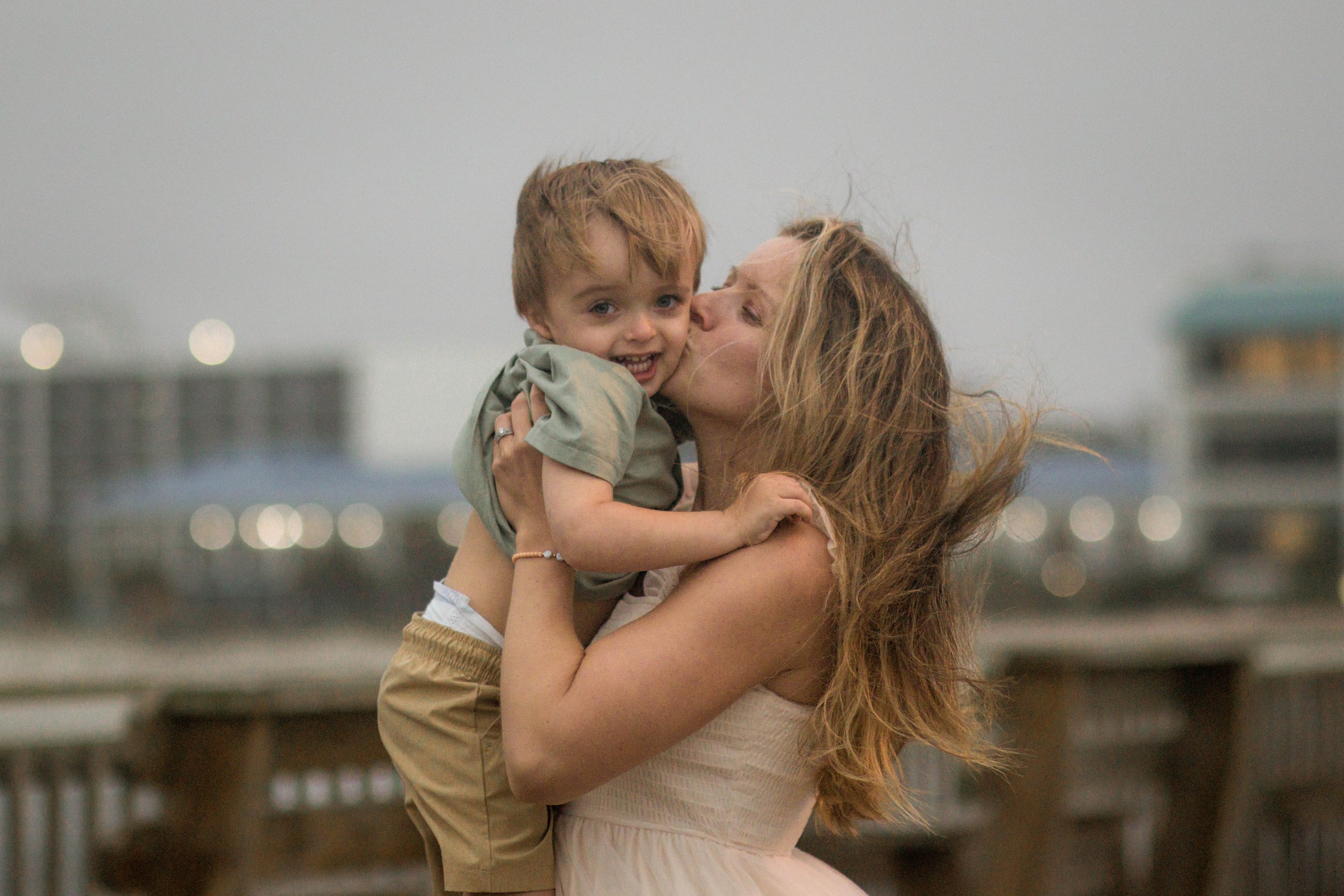 Family playing together during a windy beach photo session at Springmaid Pier in Myrtle Beach.
