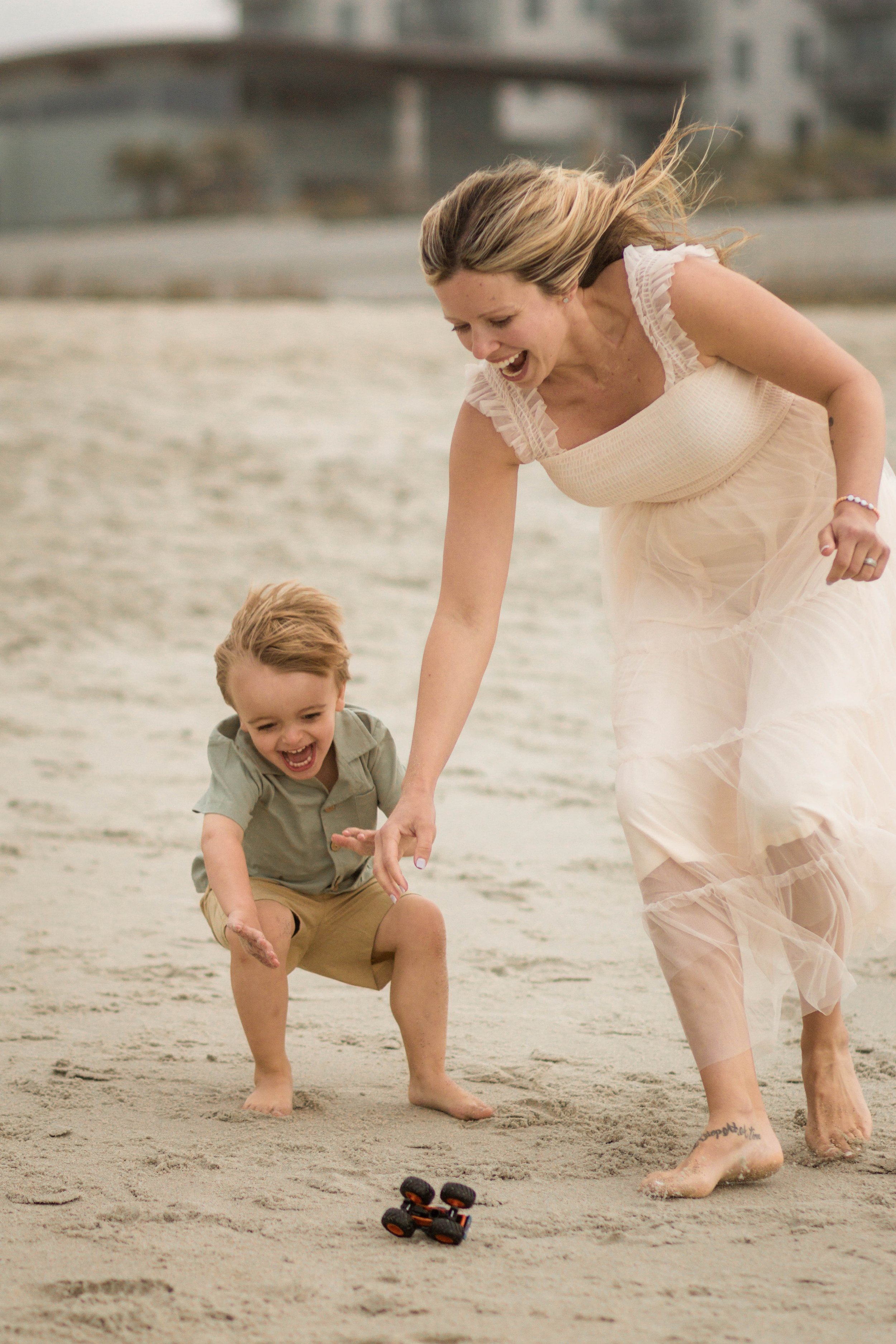 Family playing together during a windy beach photo session at Springmaid Pier in Myrtle Beach.