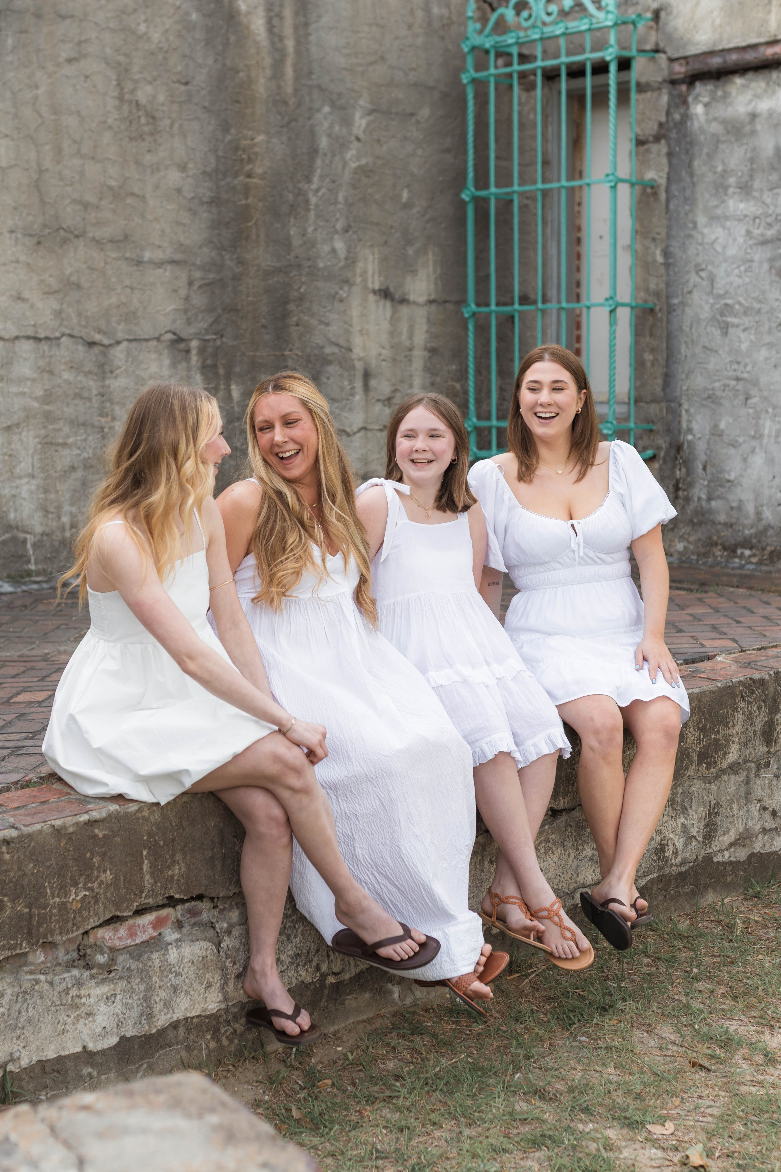 Mother and three daughters smiling and walking barefoot along the shoreline at sunset, Huntington Beach State Park