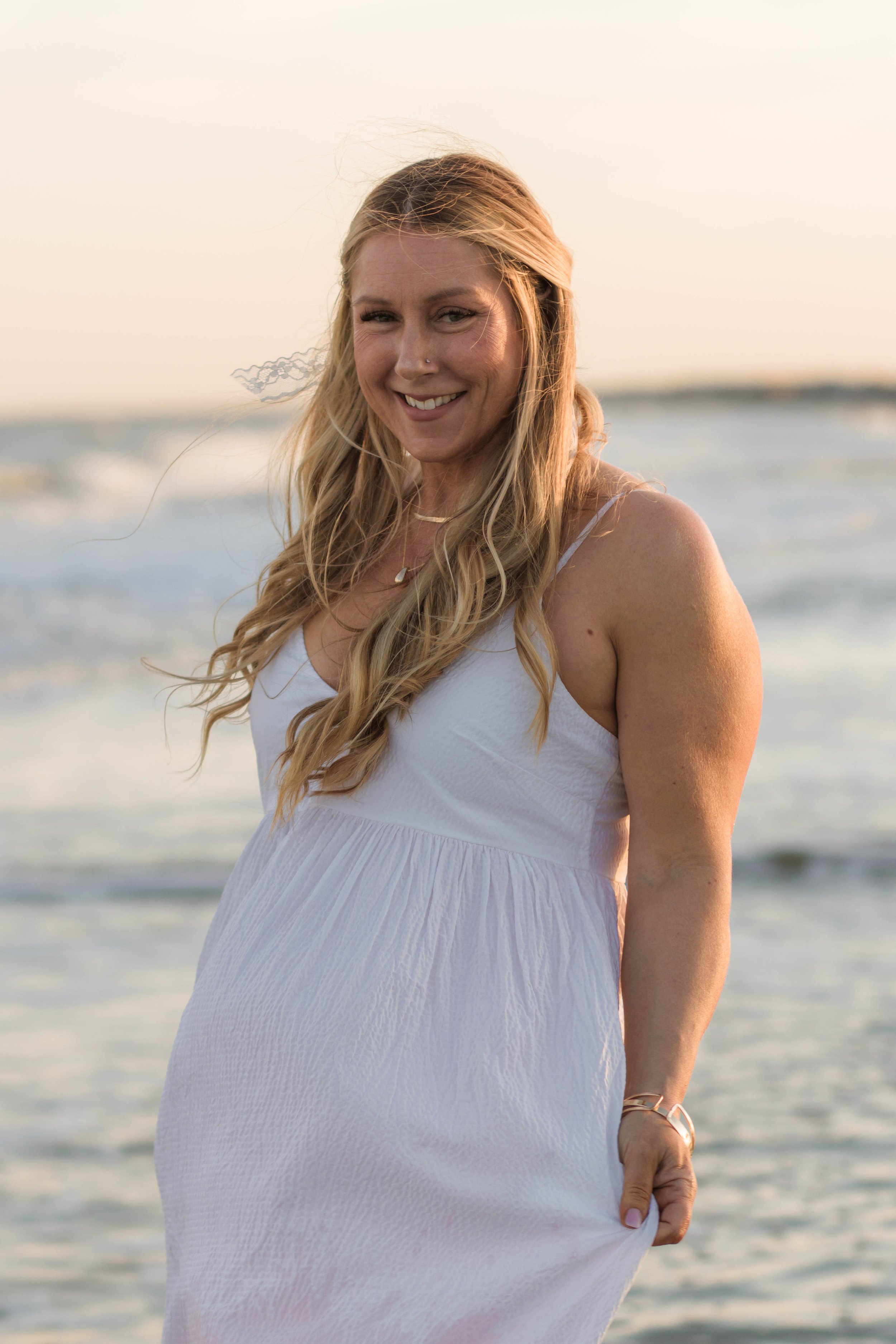 Mother and three daughters smiling and walking barefoot along the shoreline at sunset, Huntington Beach State Park