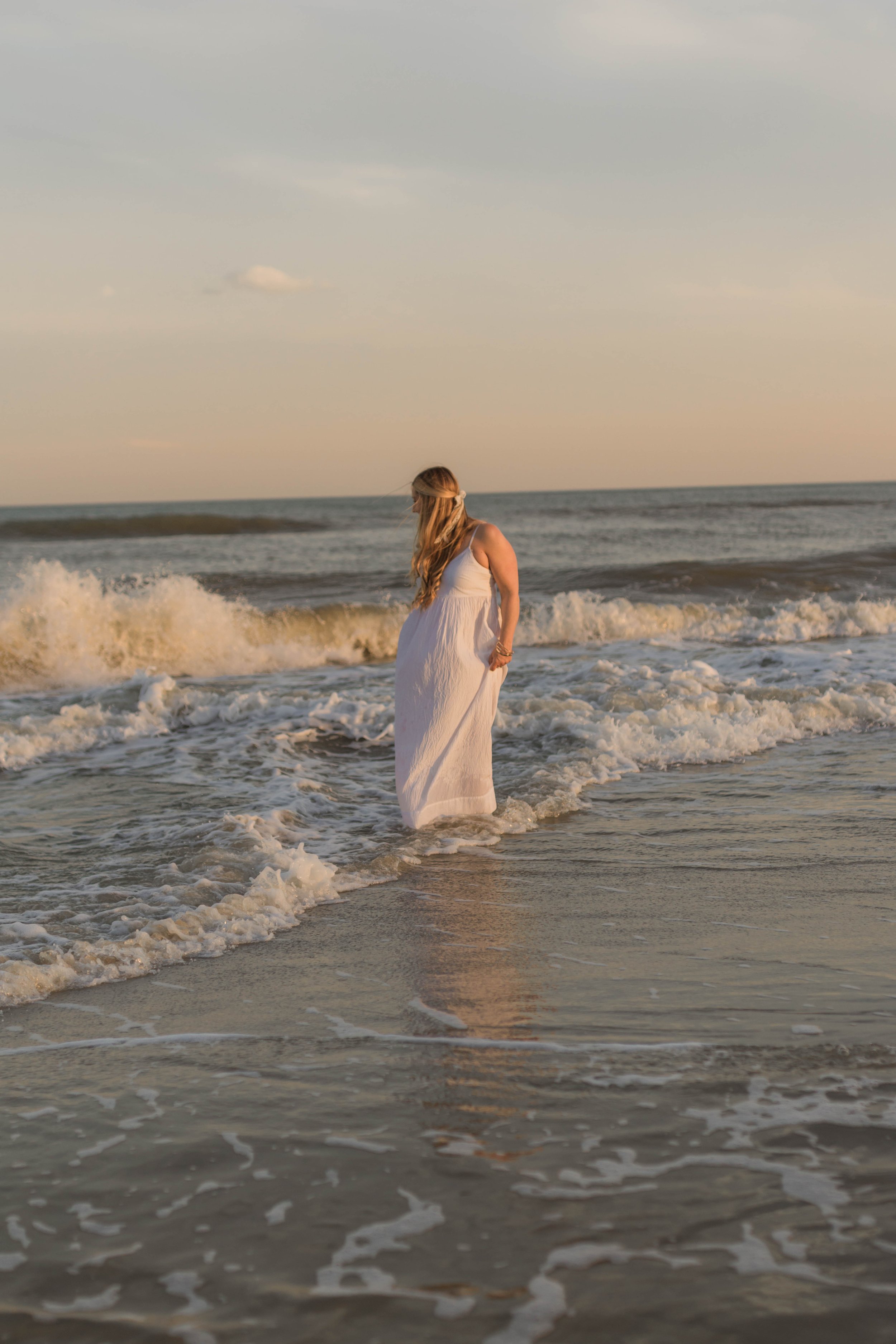 Mother and three daughters smiling and walking barefoot along the shoreline at sunset, Huntington Beach State Park