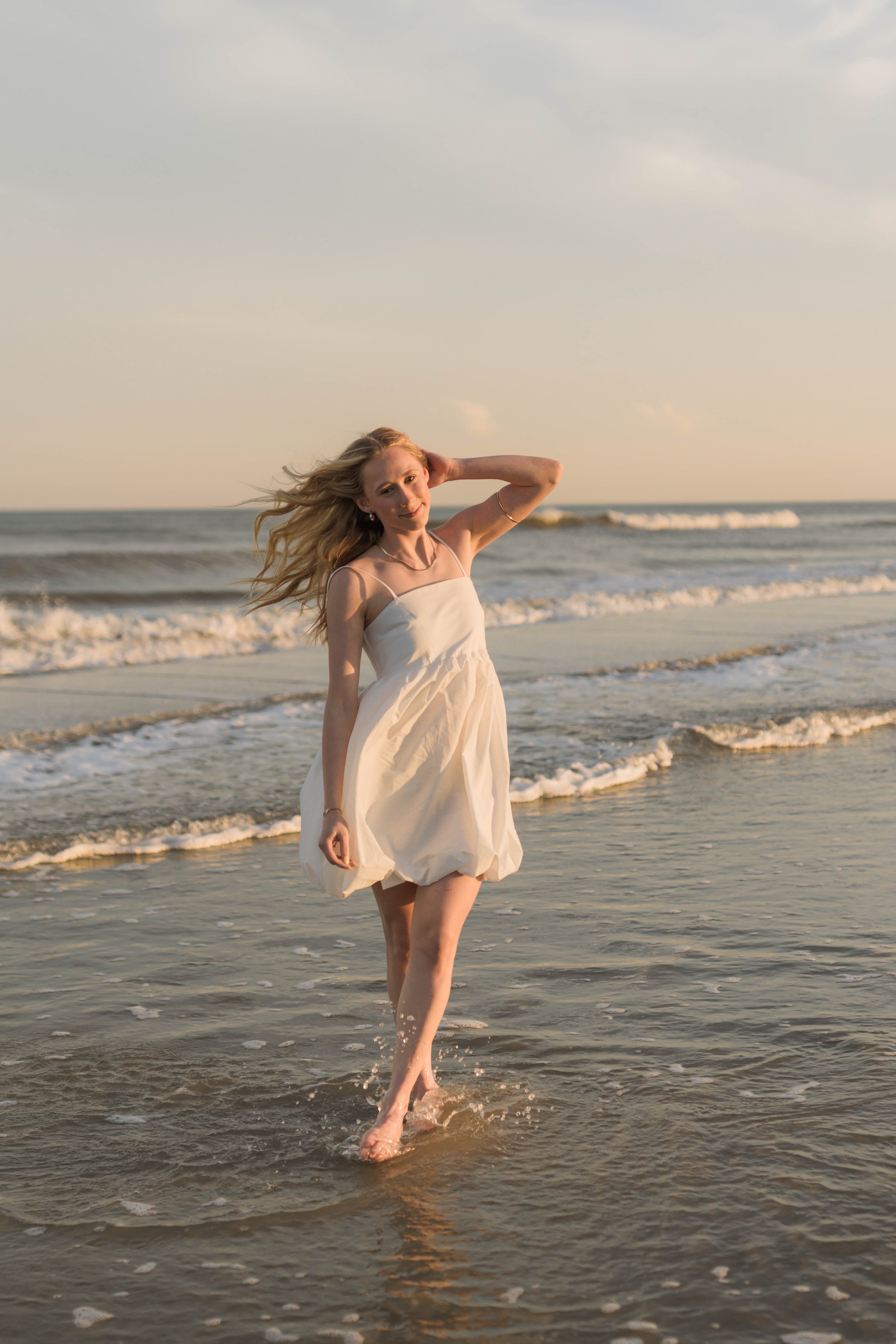Mother and three daughters smiling and walking barefoot along the shoreline at sunset, Huntington Beach State Park