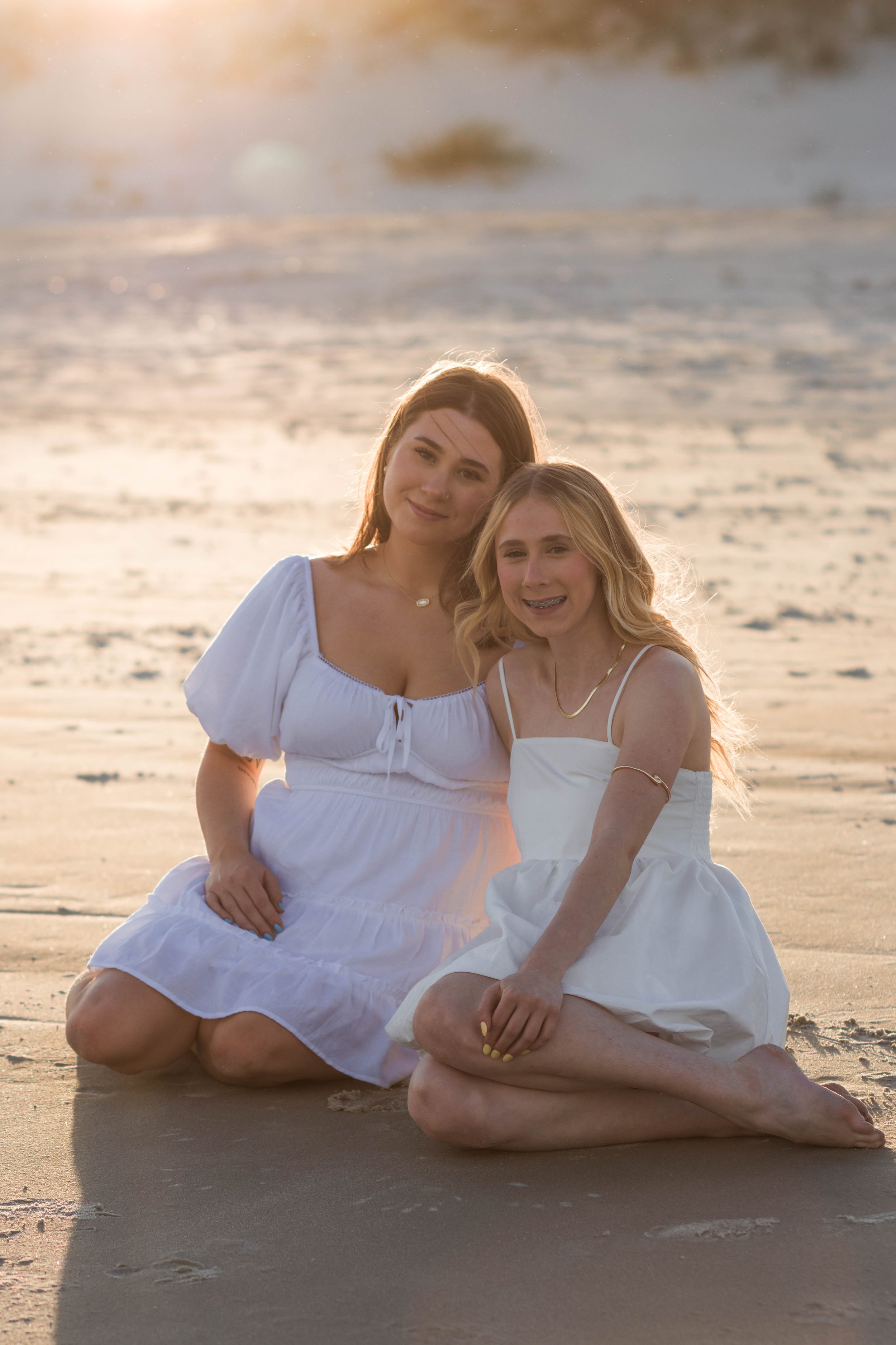 Mother and three daughters smiling and walking barefoot along the shoreline at sunset, Huntington Beach State Park