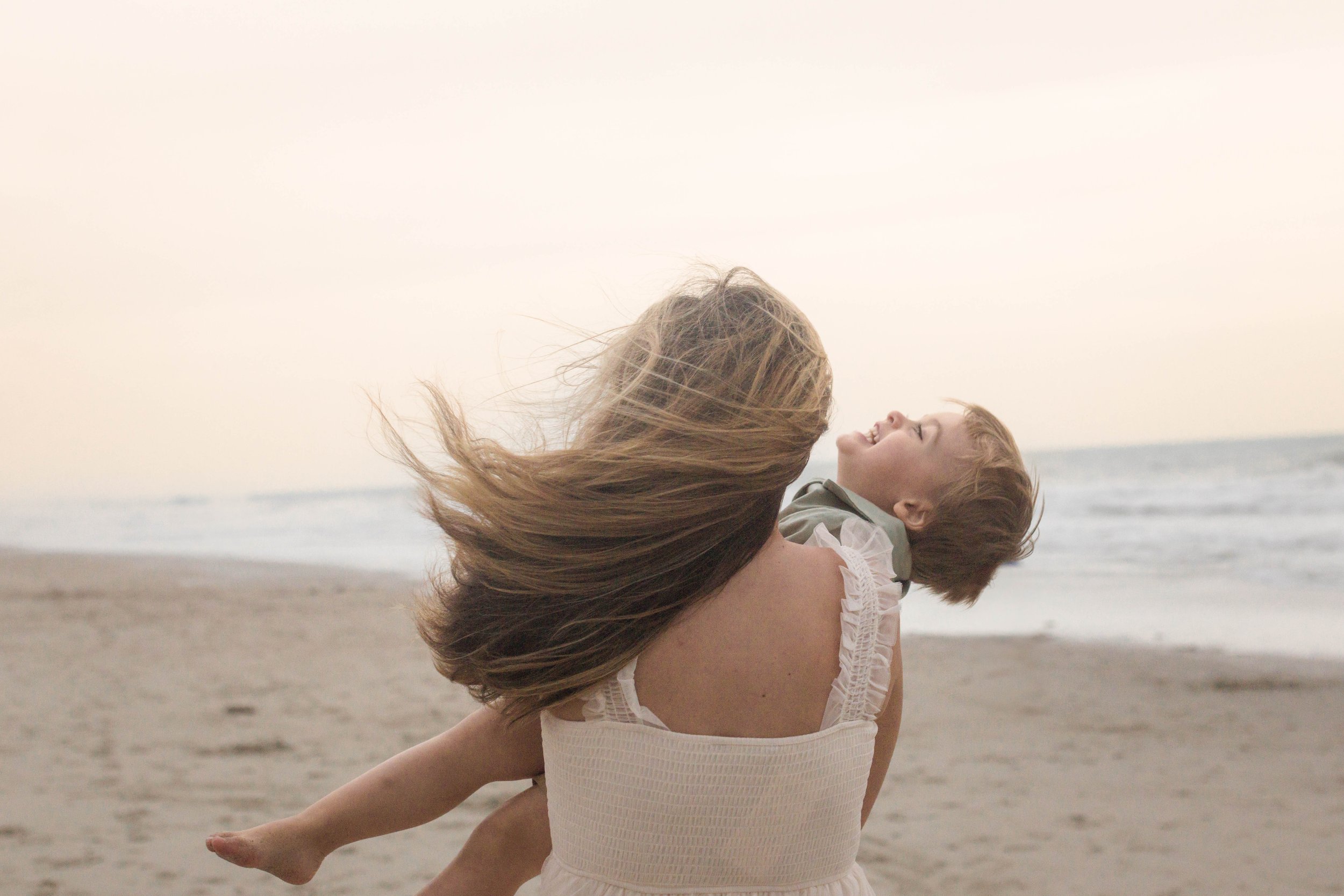 Family playing together during a windy beach photo session at Springmaid Pier in Myrtle Beach.