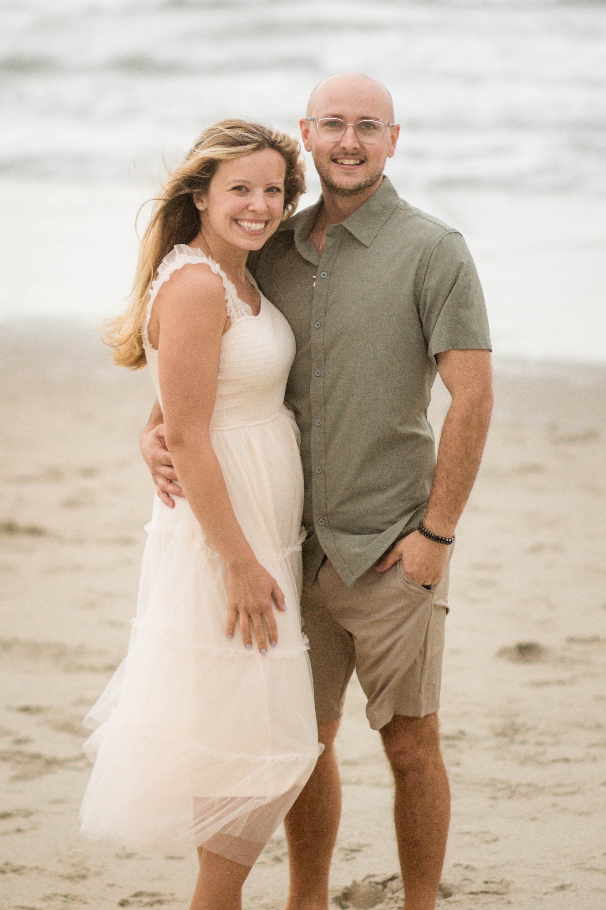 Family playing together during a windy beach photo session at Springmaid Pier in Myrtle Beach.