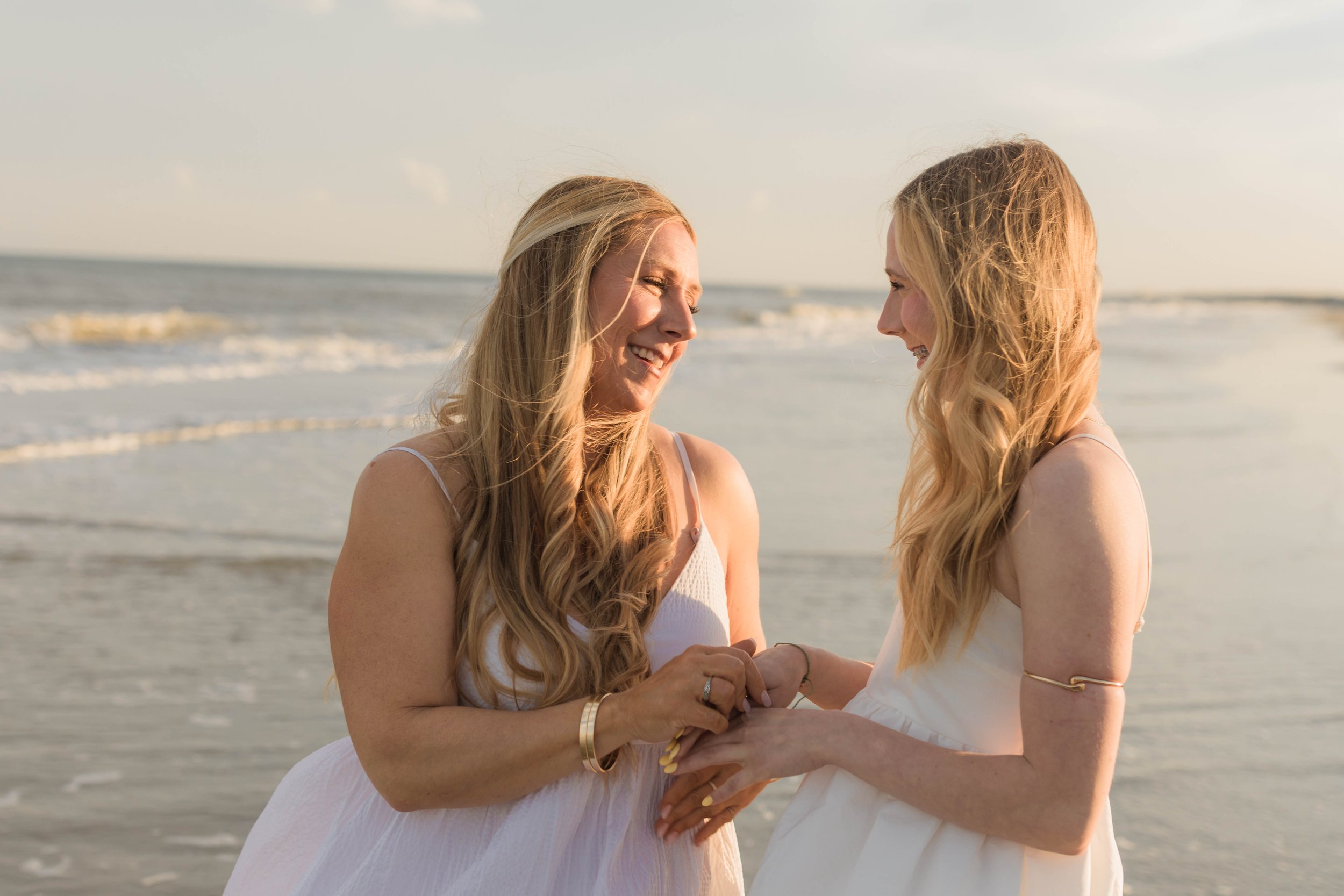 Mother and three daughters smiling and walking barefoot along the shoreline at sunset, Huntington Beach State Park