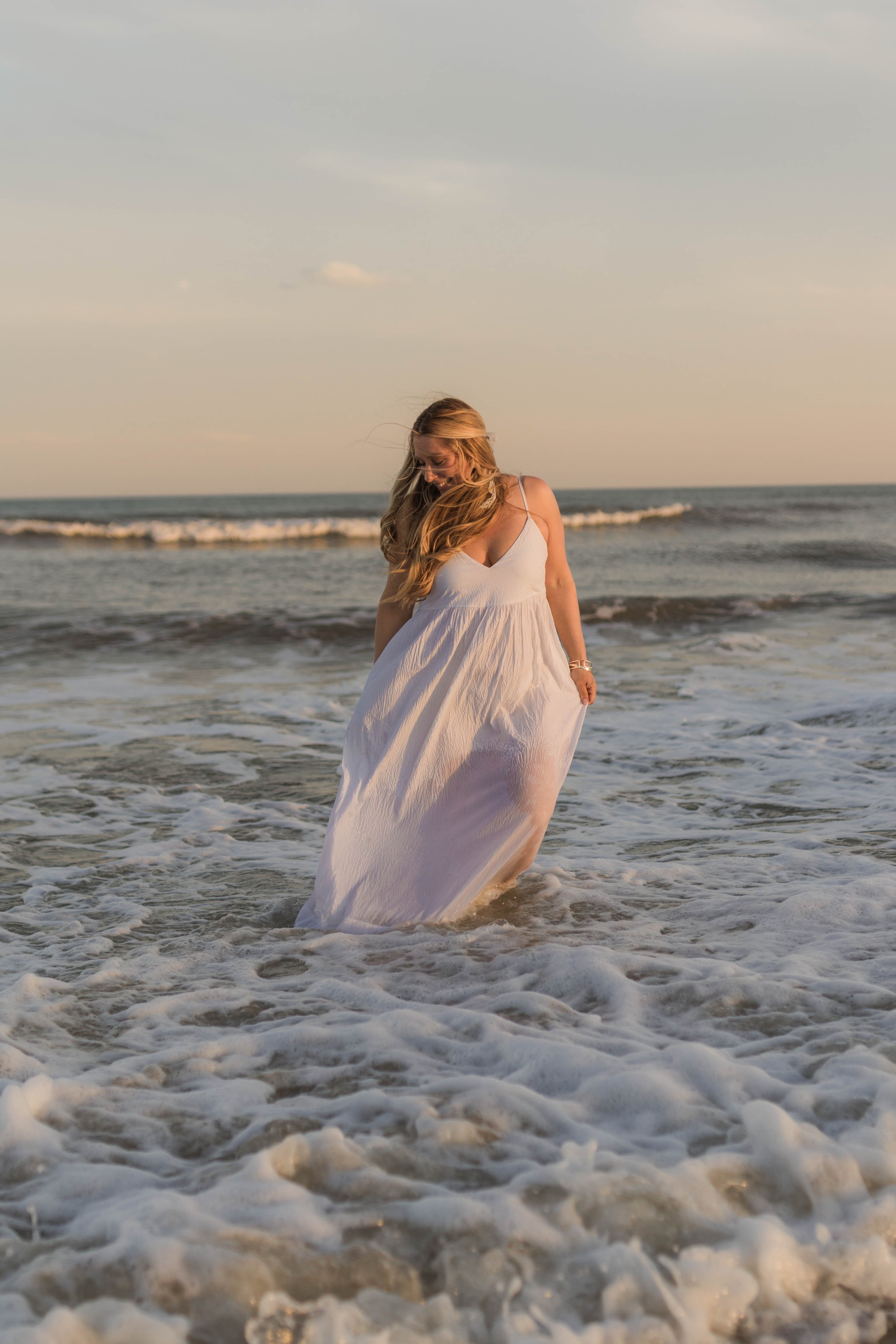 Mother and three daughters smiling and walking barefoot along the shoreline at sunset, Huntington Beach State Park
