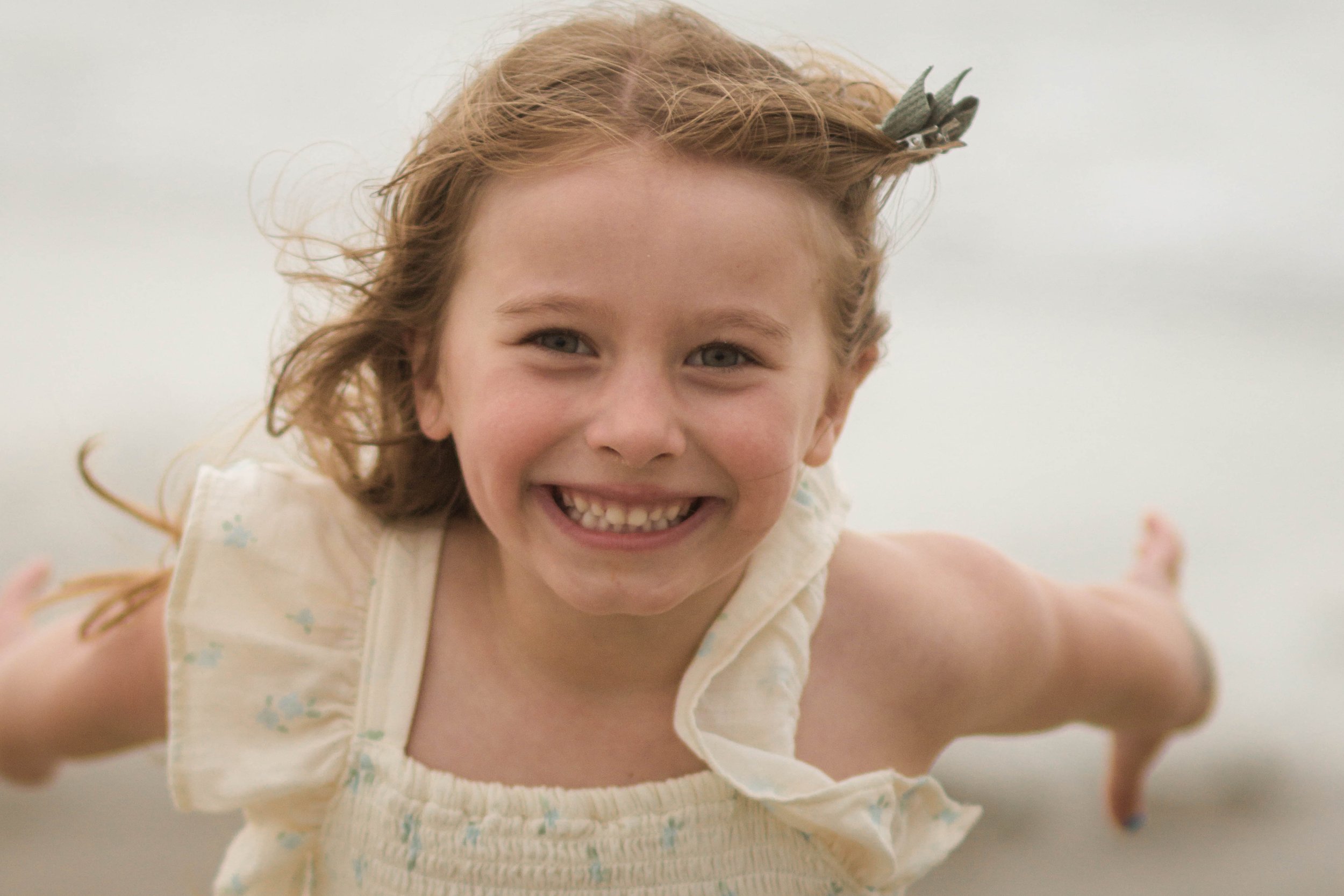 Family playing together during a windy beach photo session at Springmaid Pier in Myrtle Beach.