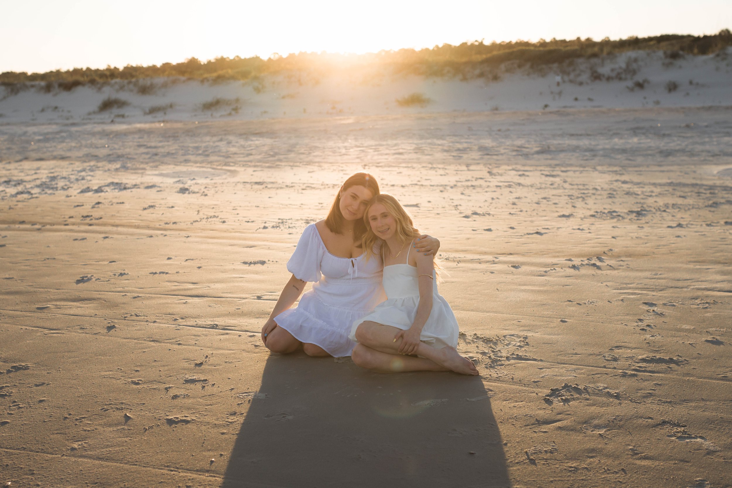 Mother and three daughters smiling and walking barefoot along the shoreline at sunset, Huntington Beach State Park