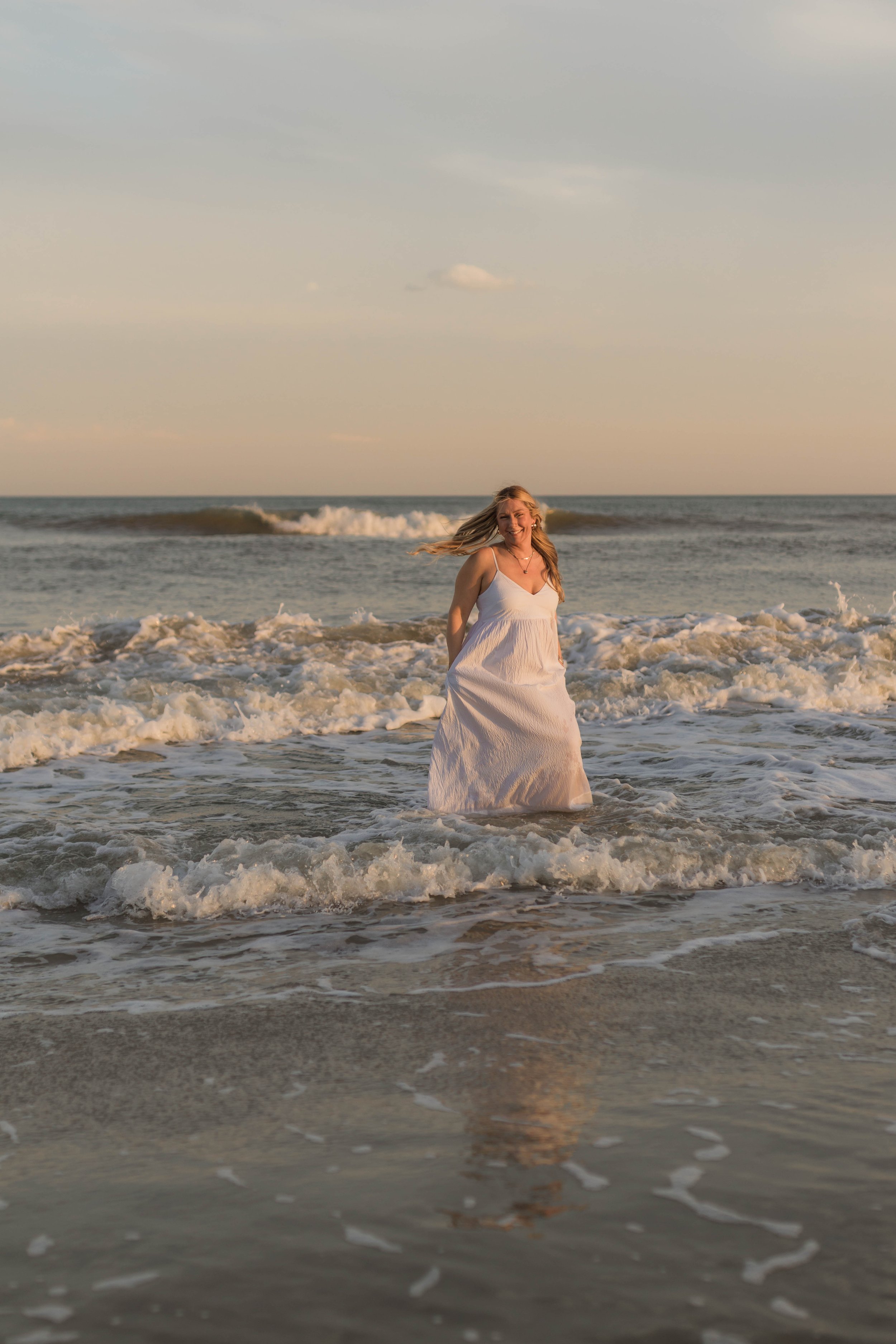 Mother and three daughters smiling and walking barefoot along the shoreline at sunset, Huntington Beach State Park
