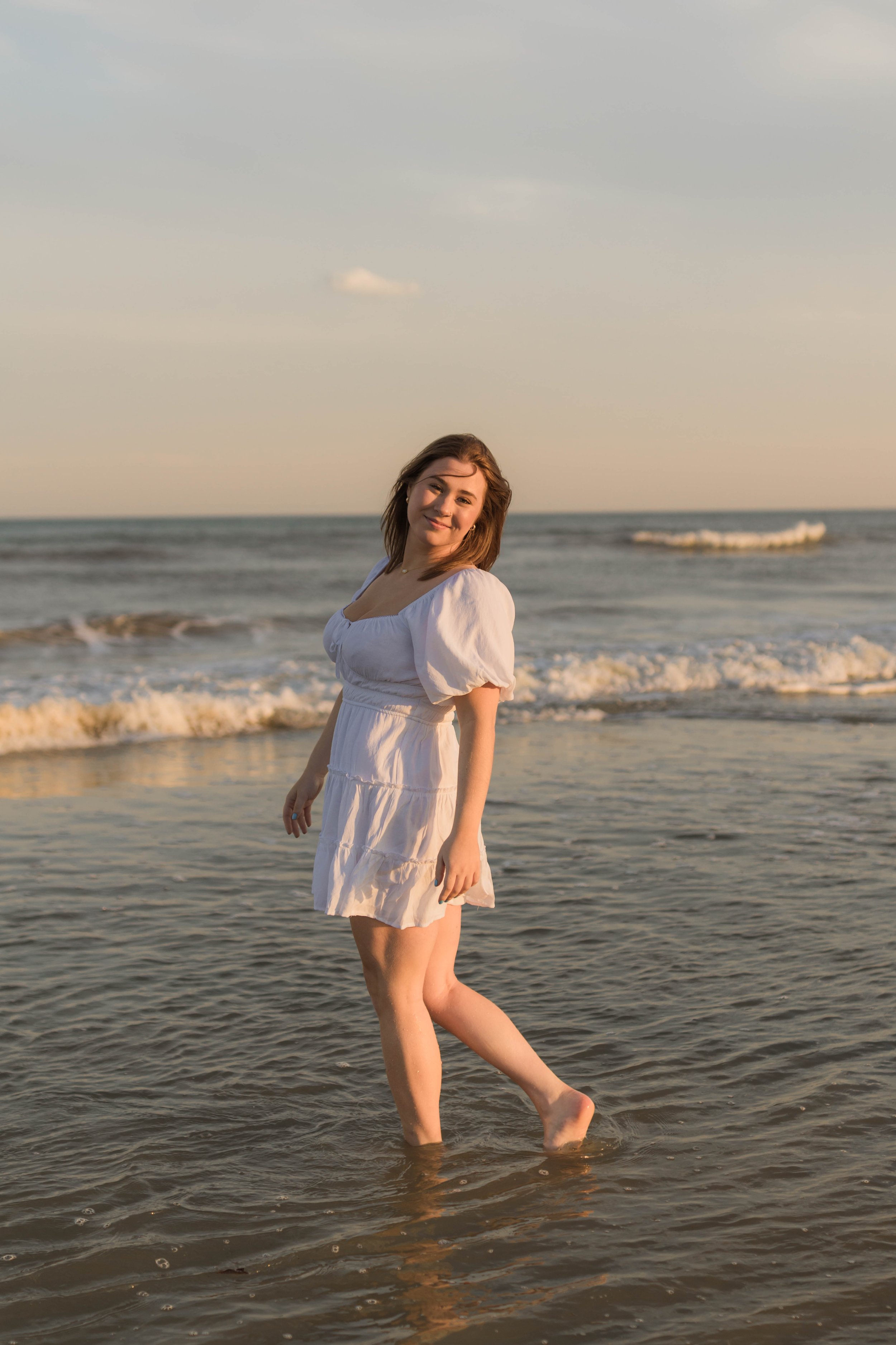 Mother and three daughters smiling and walking barefoot along the shoreline at sunset, Huntington Beach State Park