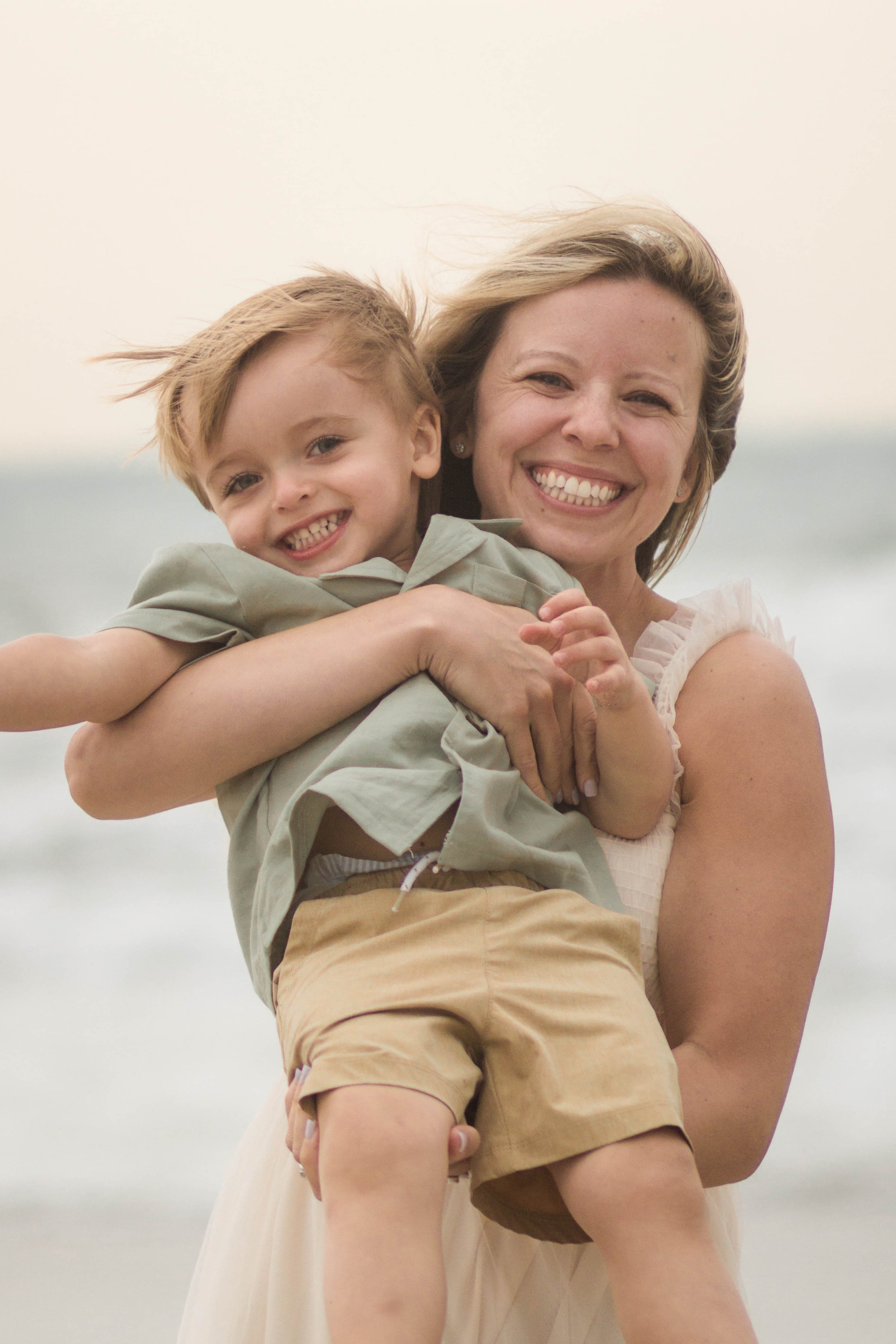 Family playing together during a windy beach photo session at Springmaid Pier in Myrtle Beach.