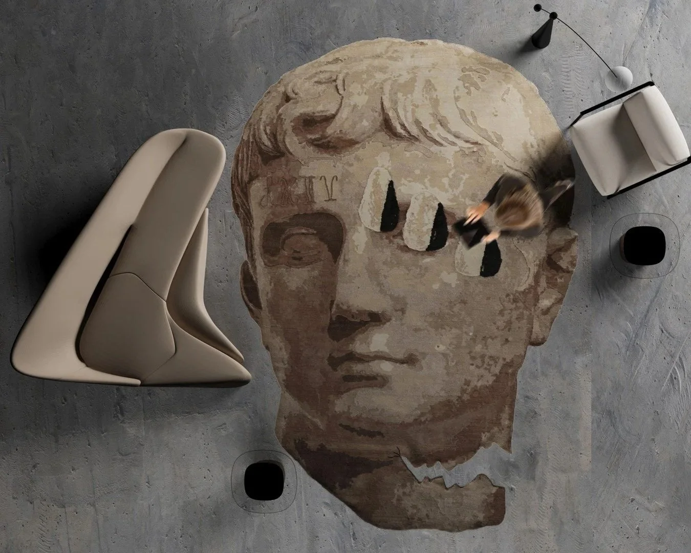 Aerial view of a sculptural Dinodo Studio rug shaped like a classical face in earthy tones, on a concrete floor beside a design sofa.