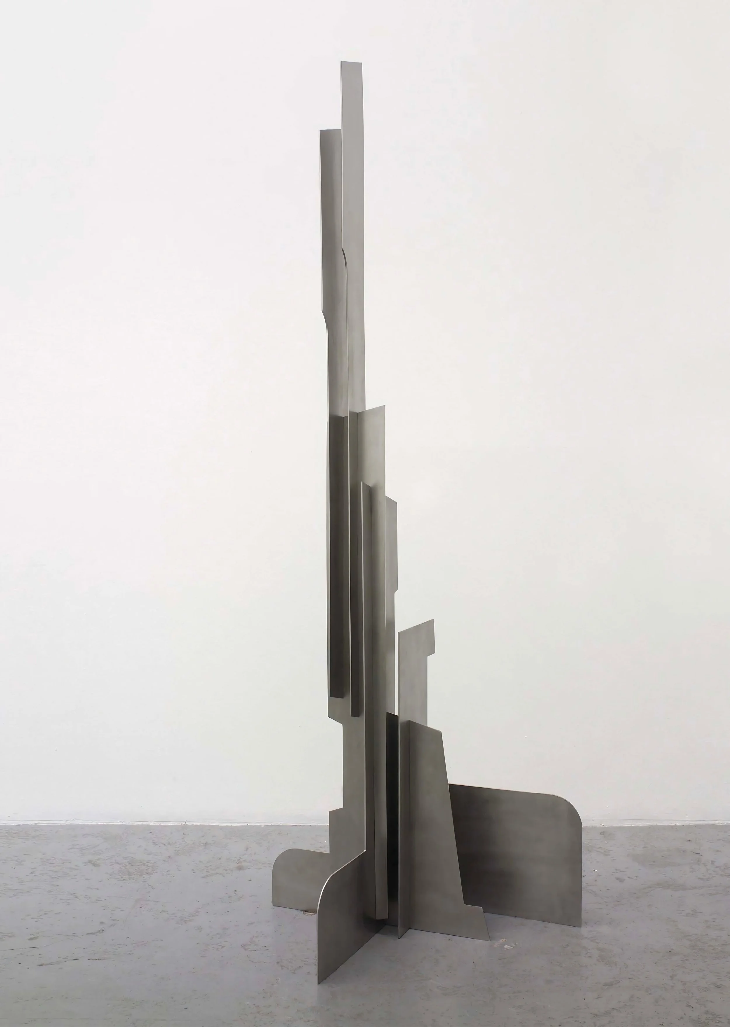 Vertical geometric steel artwork by Pablo Leonardo featuring layered architectural planes.